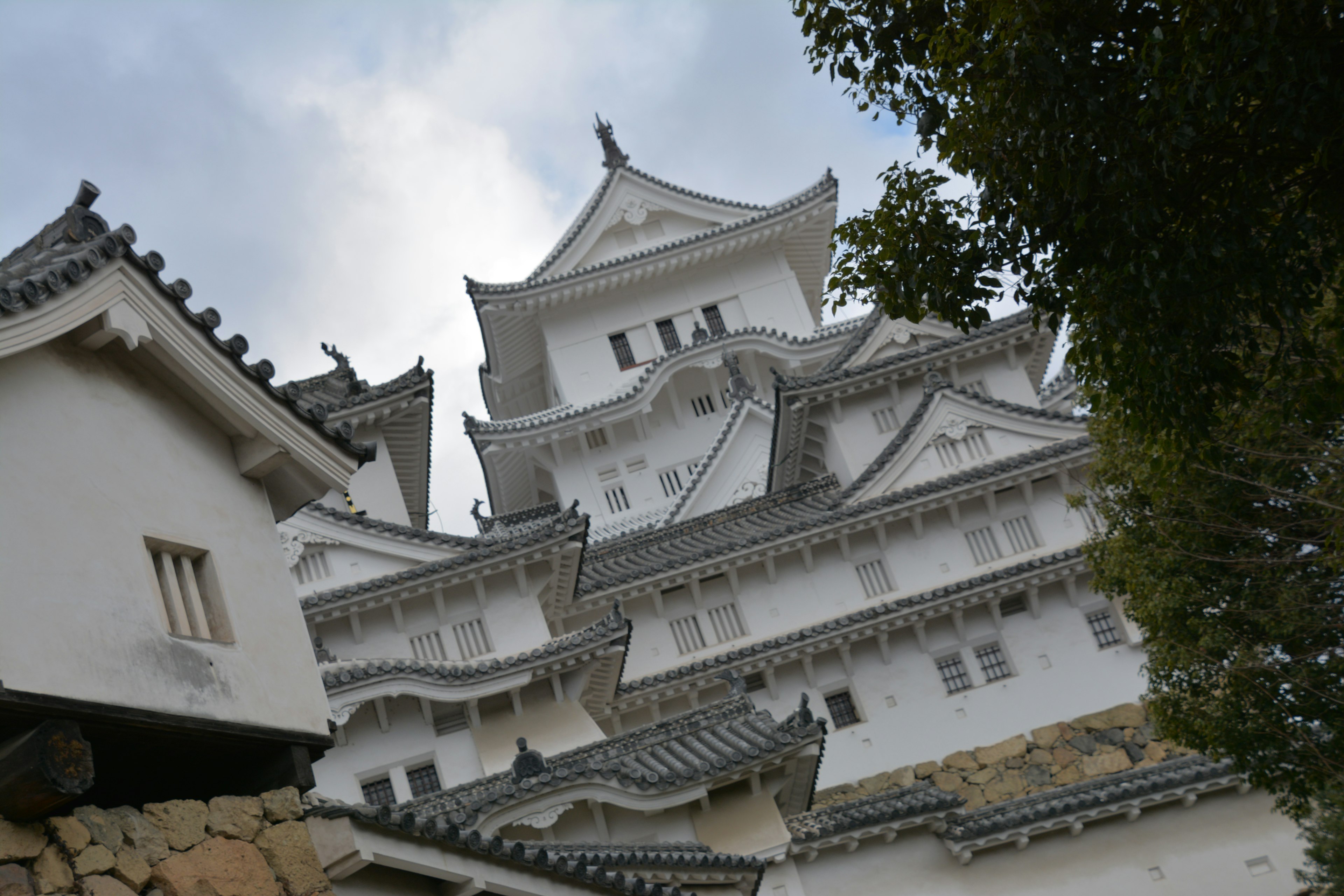 Una foto que muestra la hermosa fachada del castillo de Himeji con arquitectura histórica y naturaleza circundante