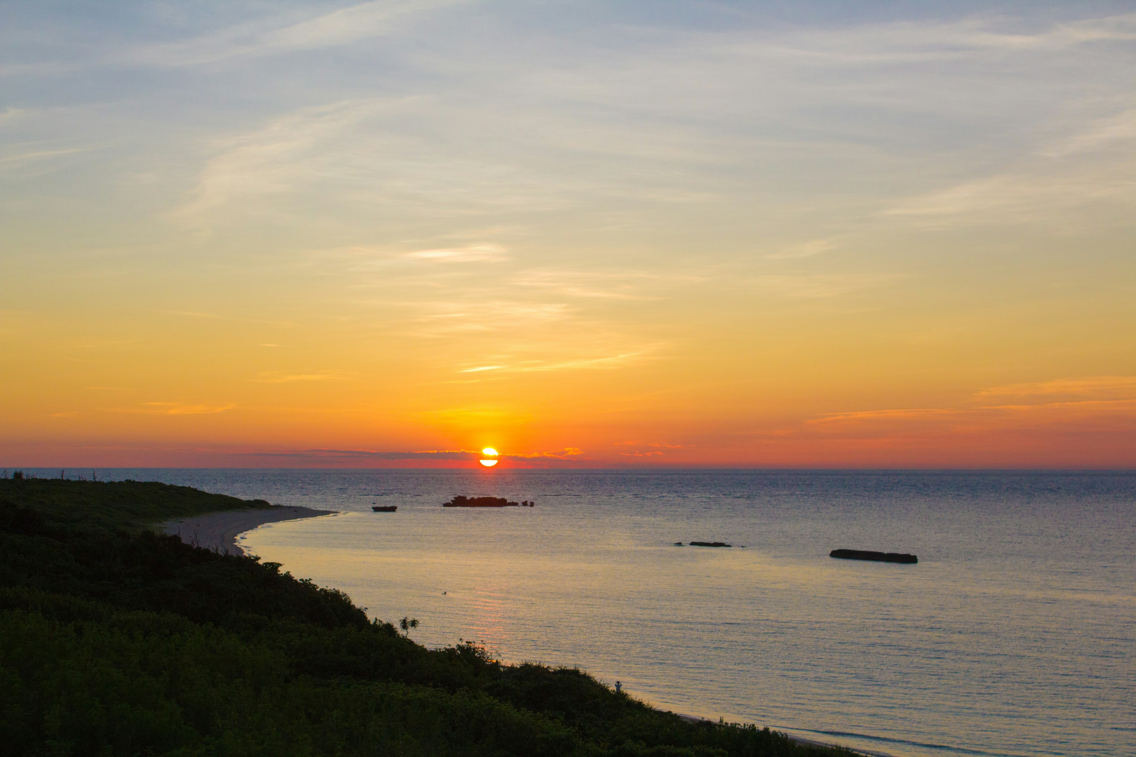 Schöne Landschaft mit Sonnenuntergang über dem Meer grüne Hügel und ruhiges Wasser