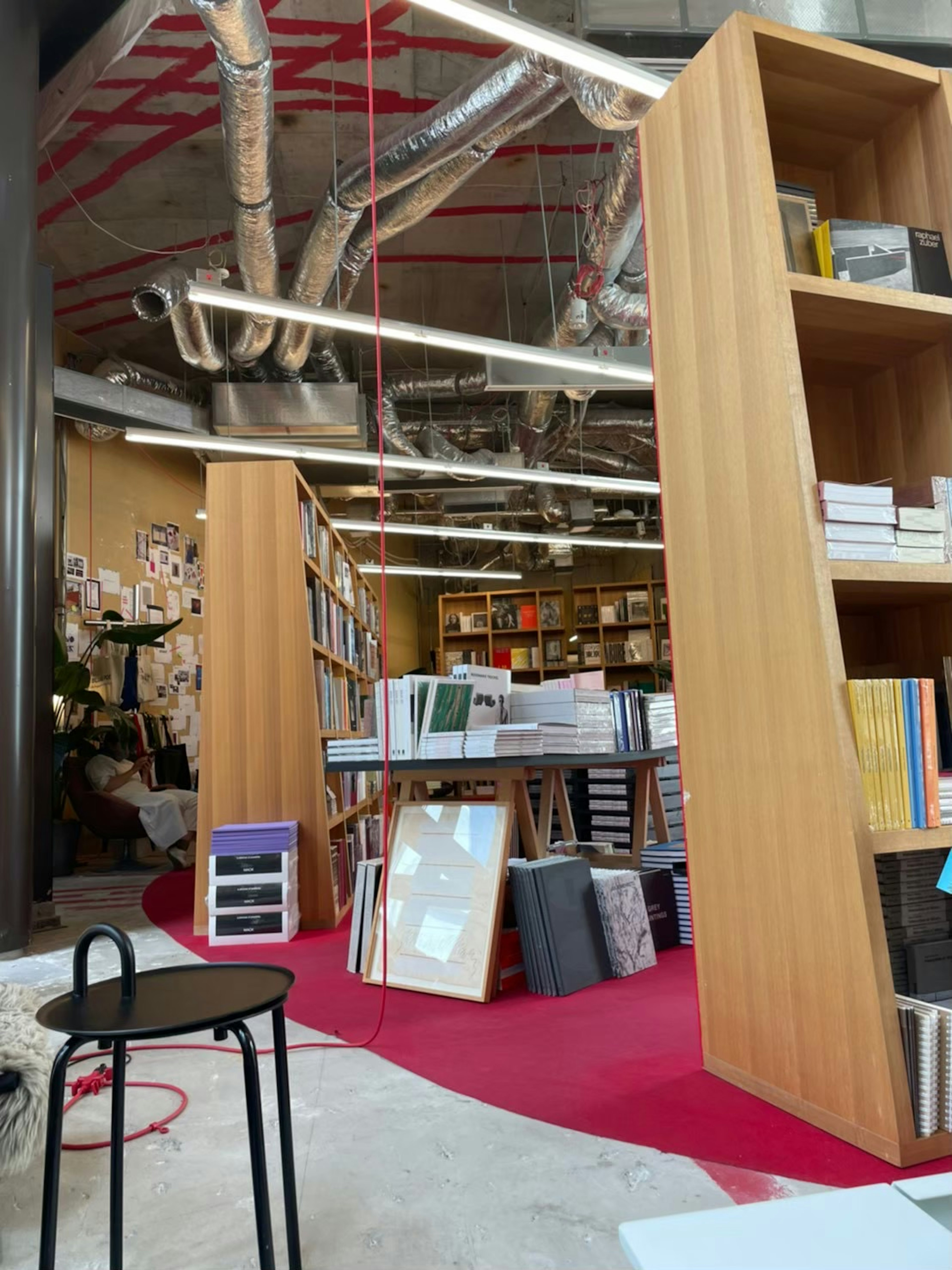 Interior of a modern bookstore featuring wooden bookshelves and stacked books on a red carpet