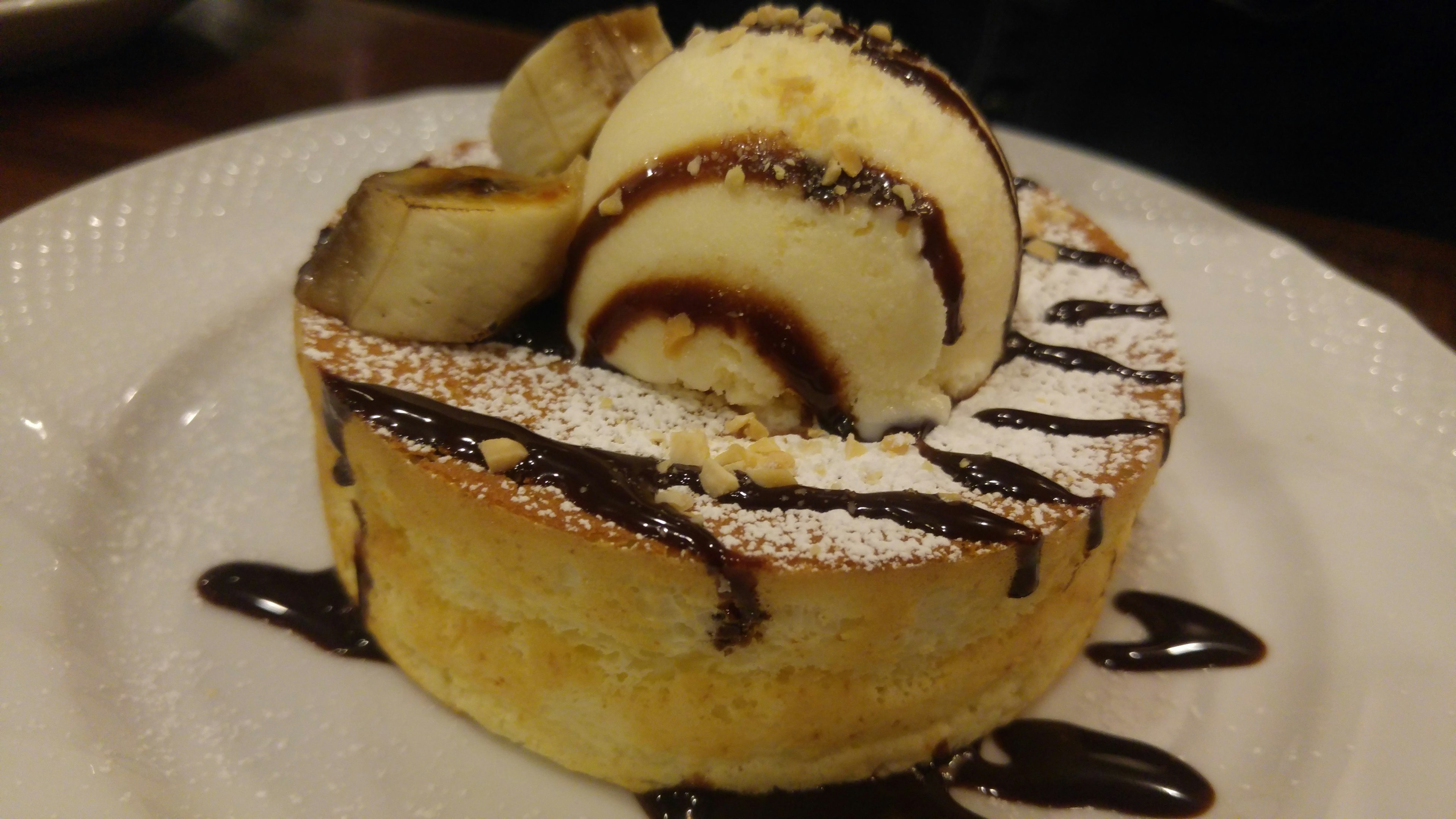 Fluffy pancake topped with banana slices and ice cream