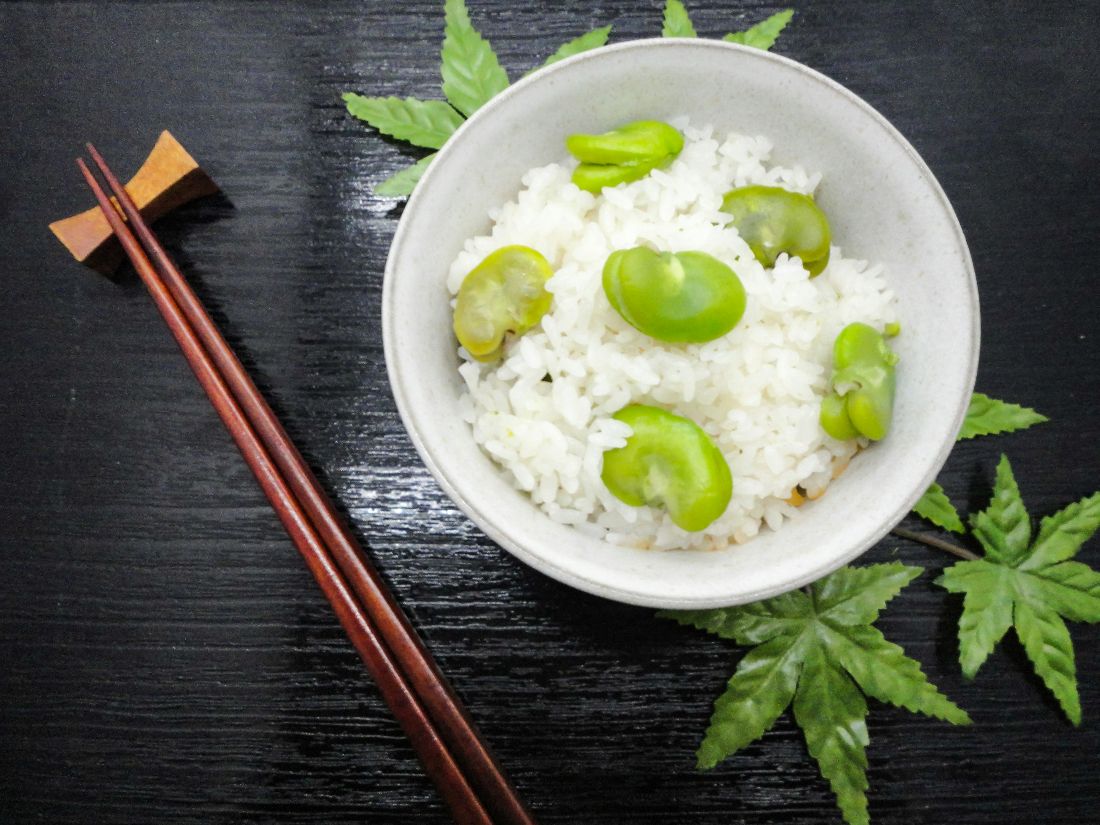 Bol de riz blanc garni de fèves placé sur des feuilles vertes