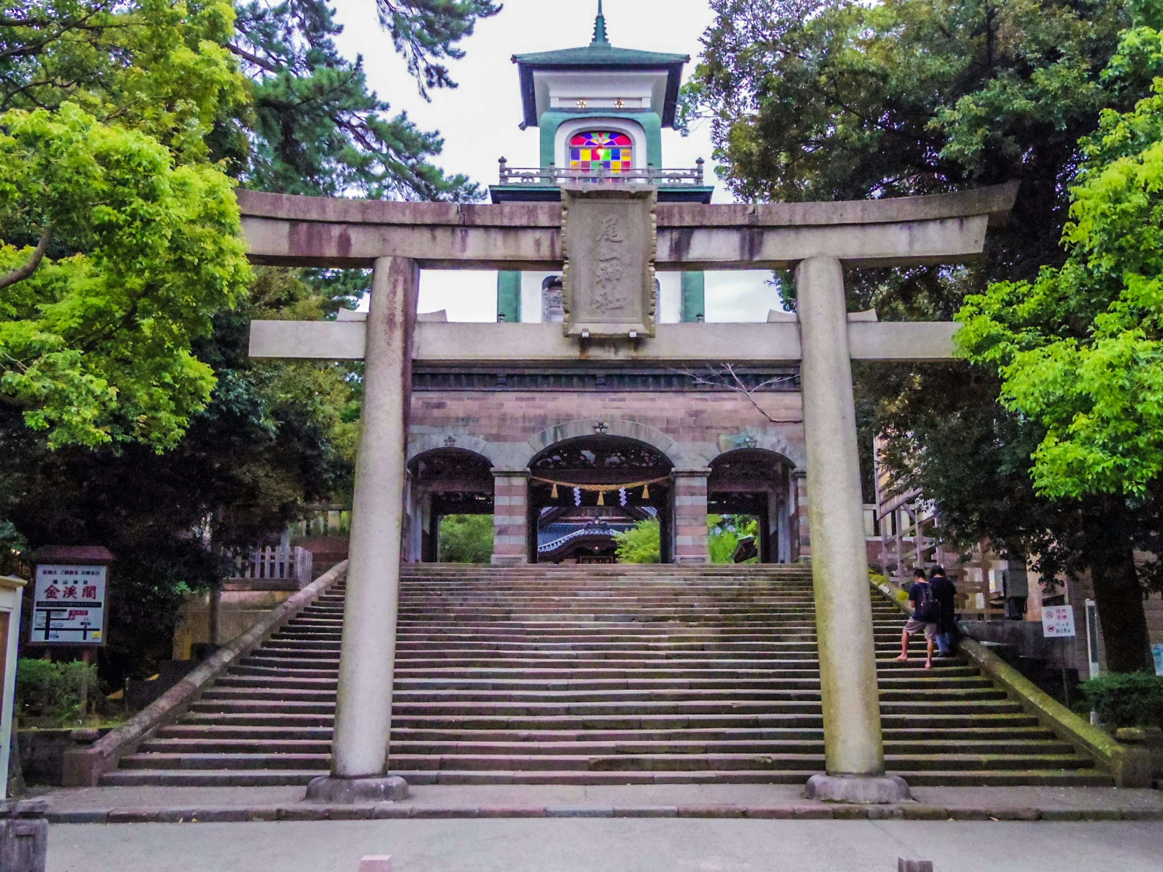 Haupteingang eines Schreins mit einem Torii und Treppen, umgeben von üppigem Grün