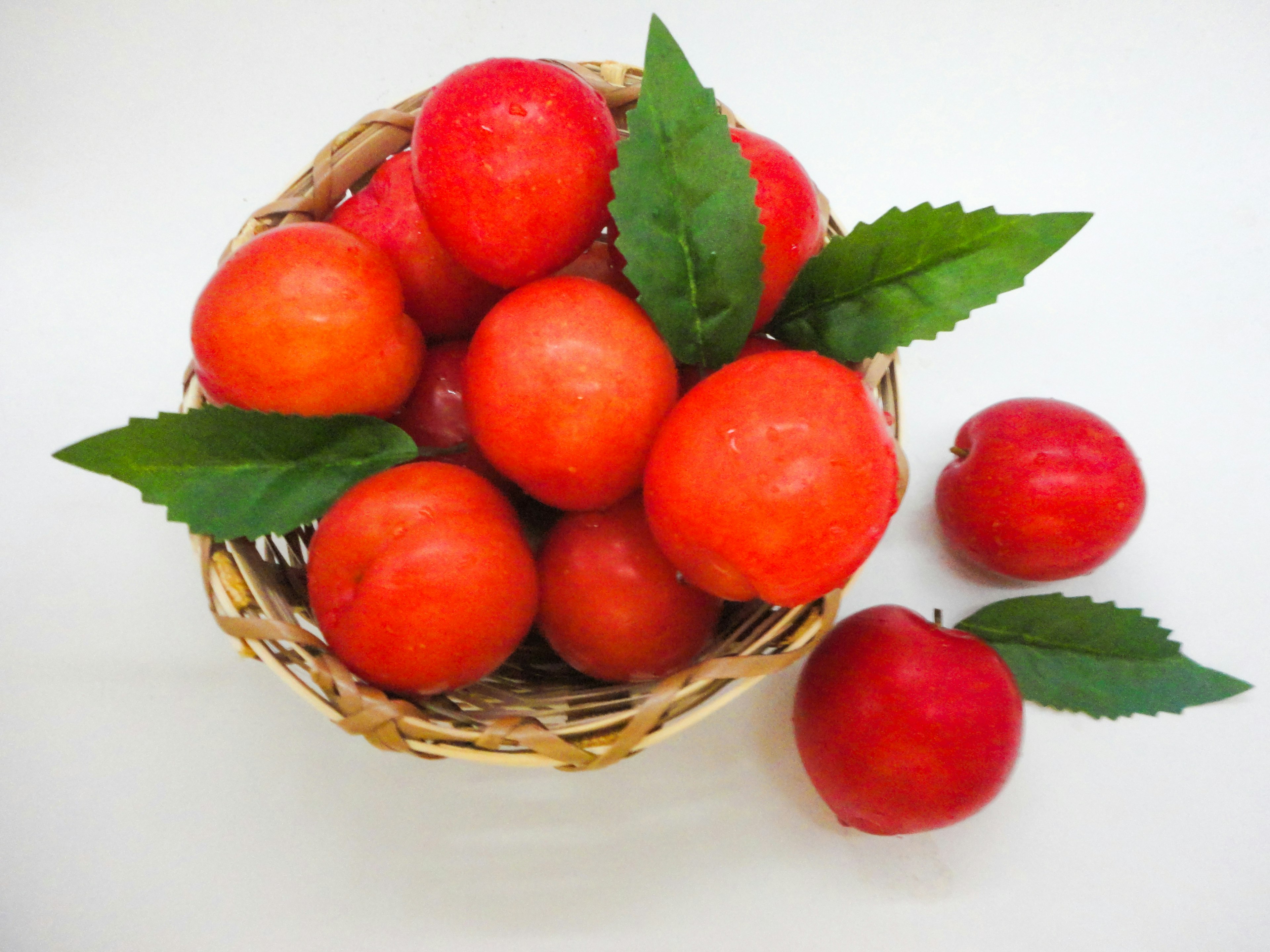 Keranjang yang penuh dengan buah merah cerah dan daun hijau