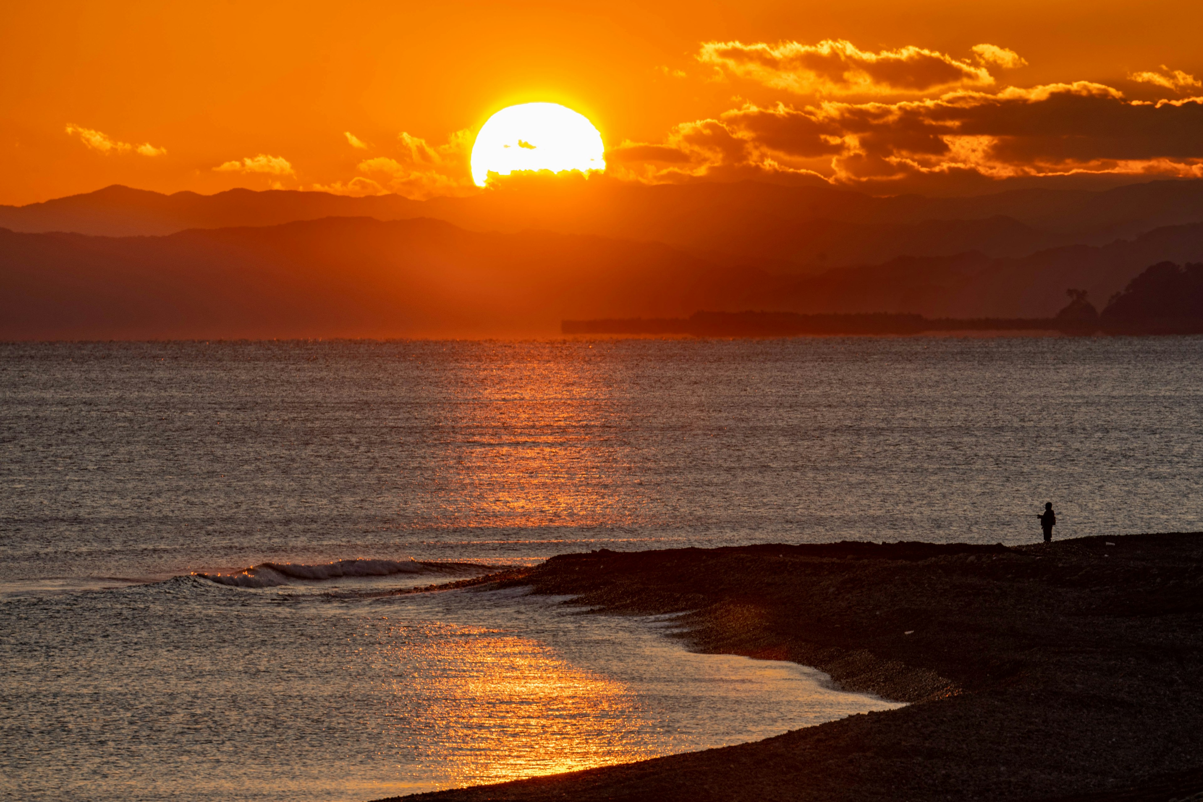 Beautiful landscape of the sunset over the sea with a silhouette standing on the beach