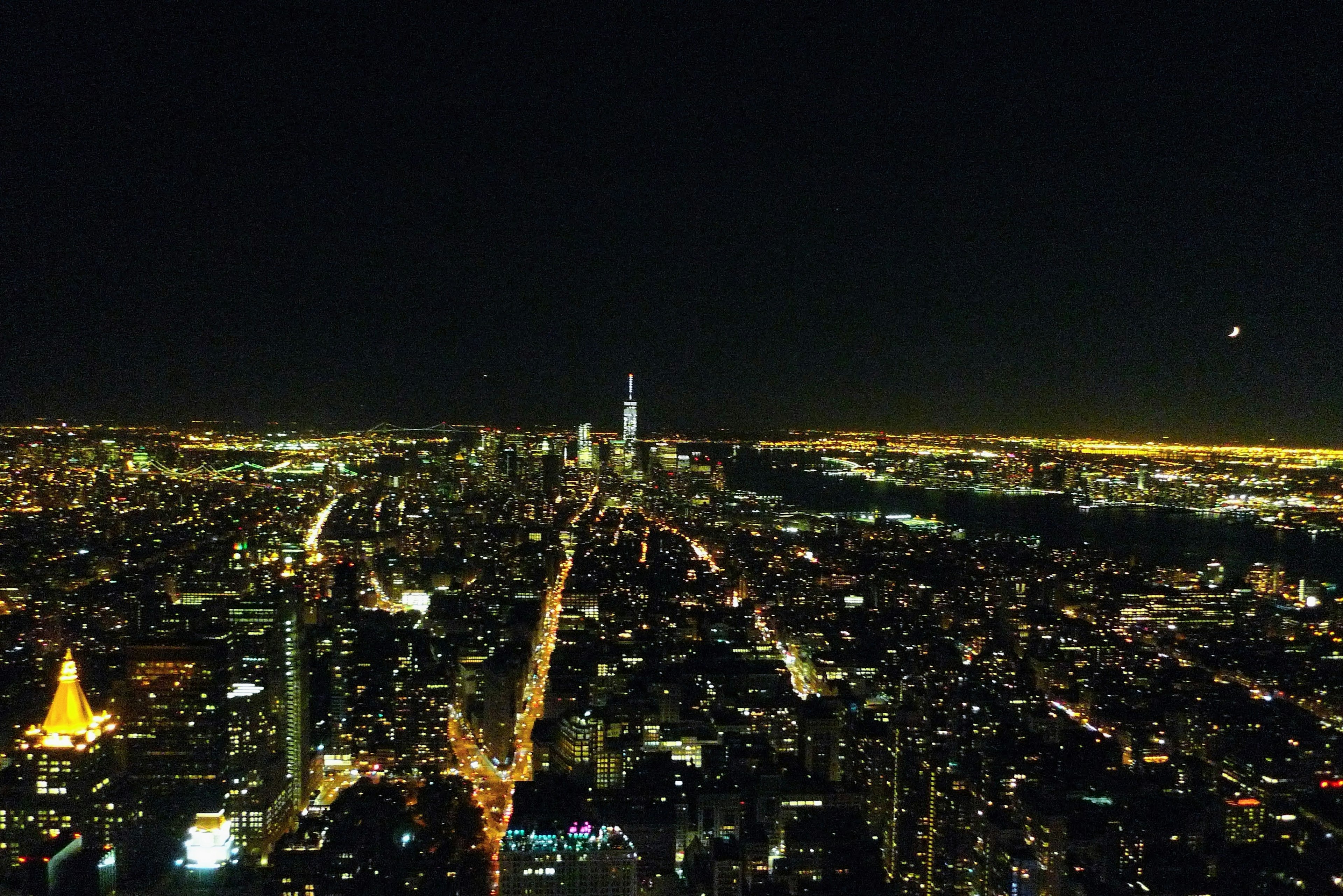 Pemandangan panorama Kota New York di malam hari dengan gedung pencakar langit yang terang dan jalan yang diterangi