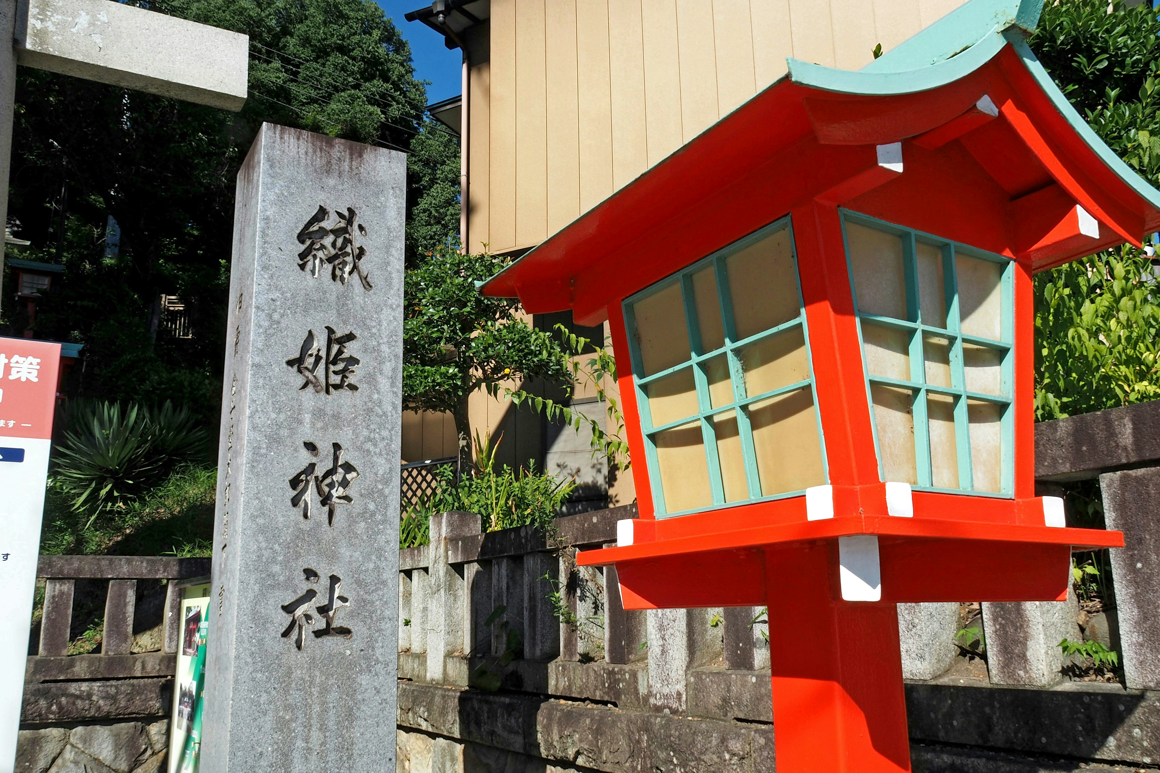 赤い灯籠と石の碑がある神社の風景