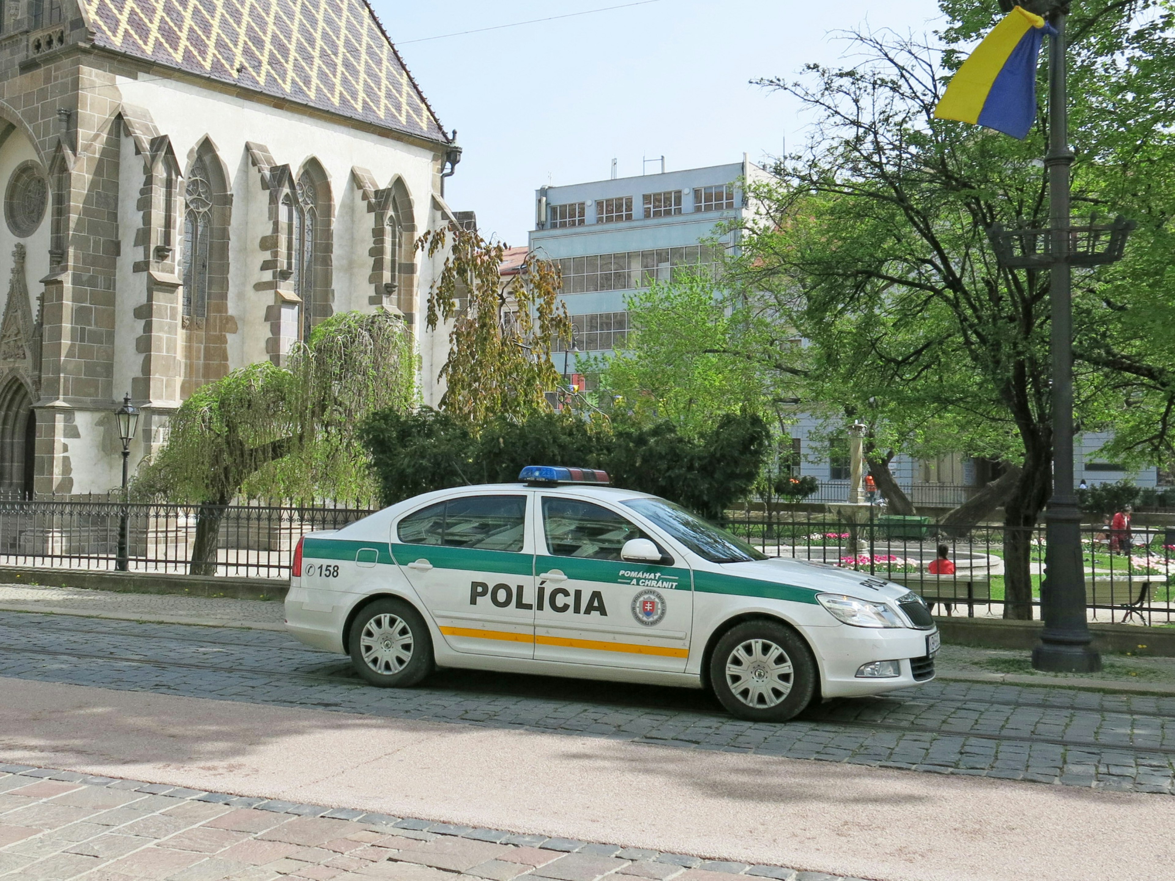 停在教堂附近的警车，背景有绿树和建筑