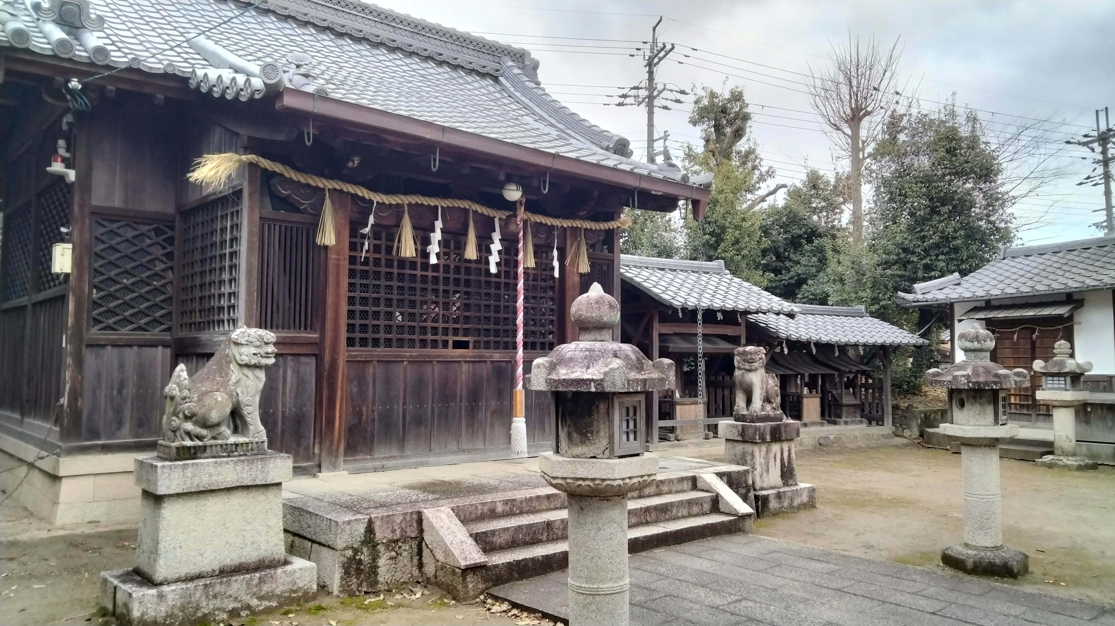 伝統的な日本の神社の風景で、木造の建物と石の灯籠が見える