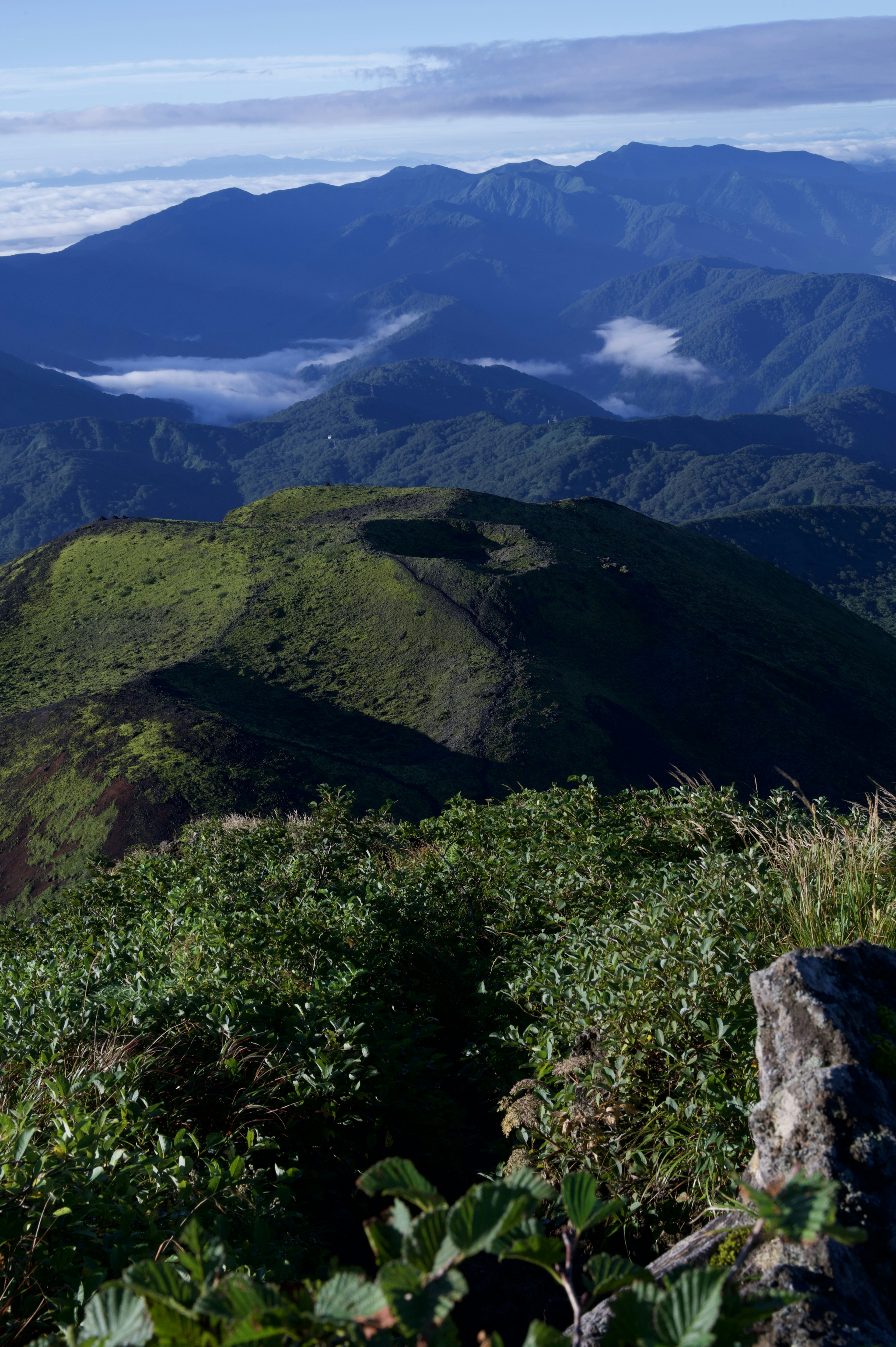 綠意盎然的山脈全景，遠處有雲