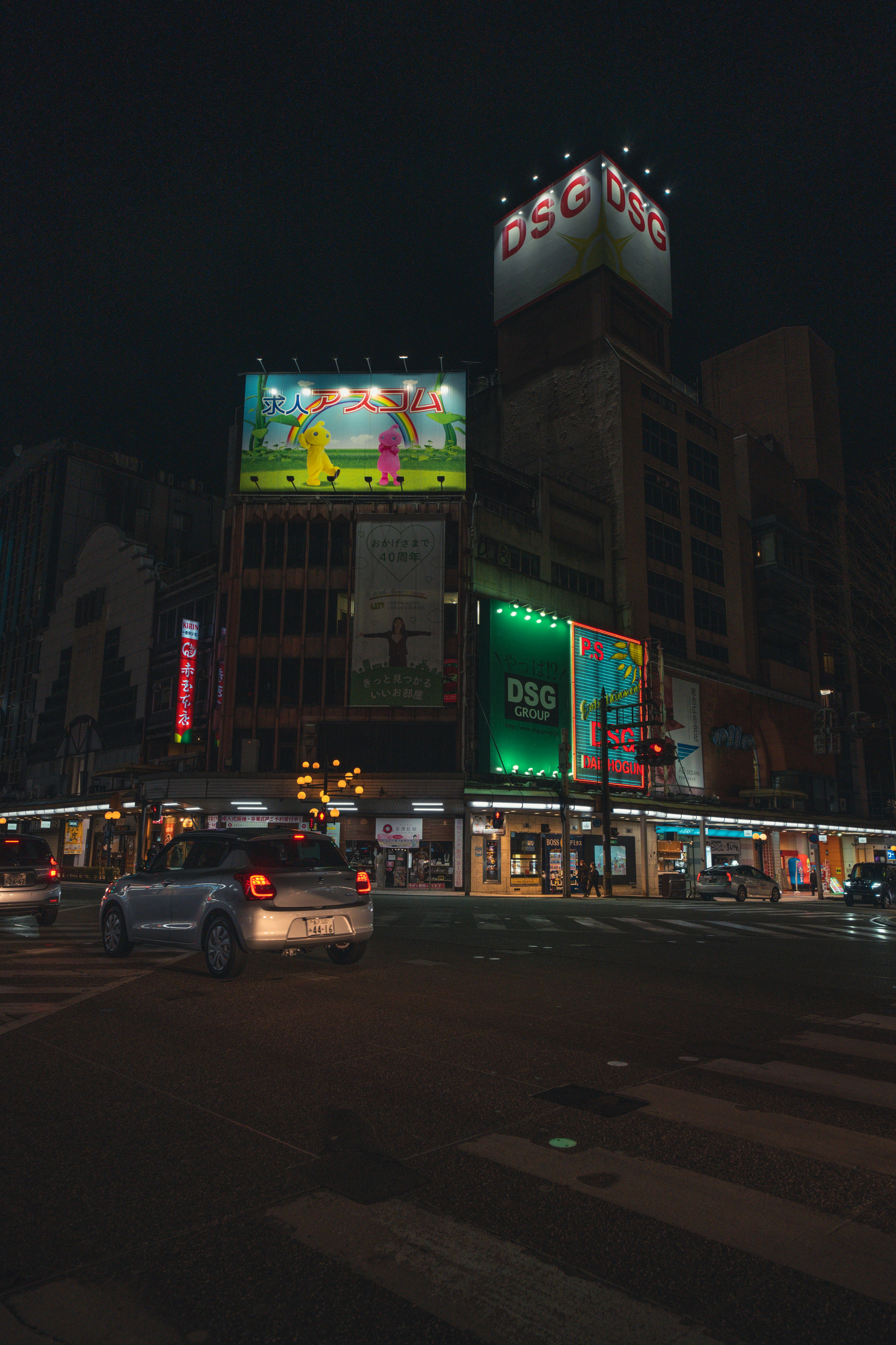 Urban scene at night featuring illuminated buildings and billboards