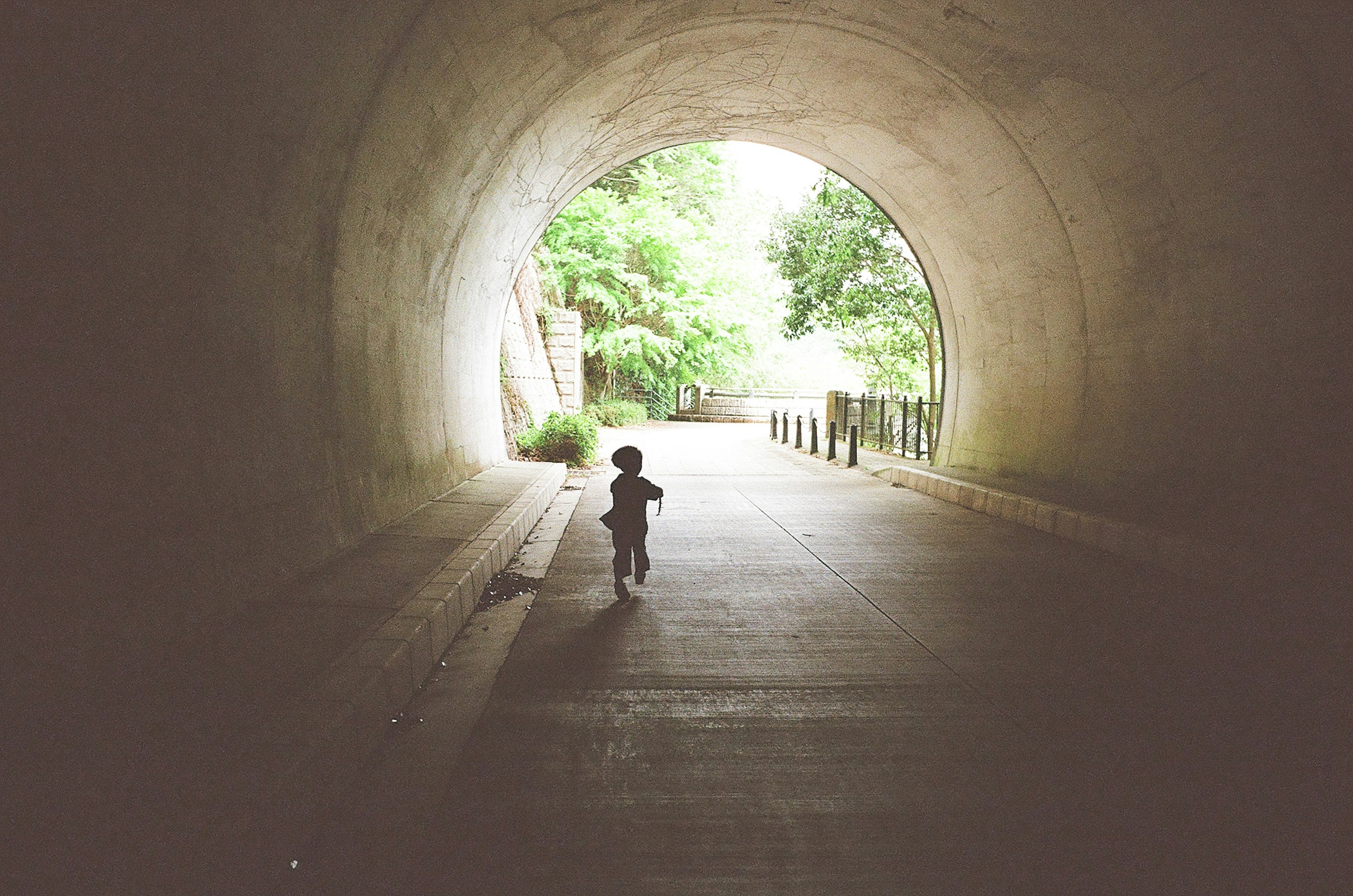 Silhouette d'un enfant courant dans un tunnel avec une sortie lumineuse