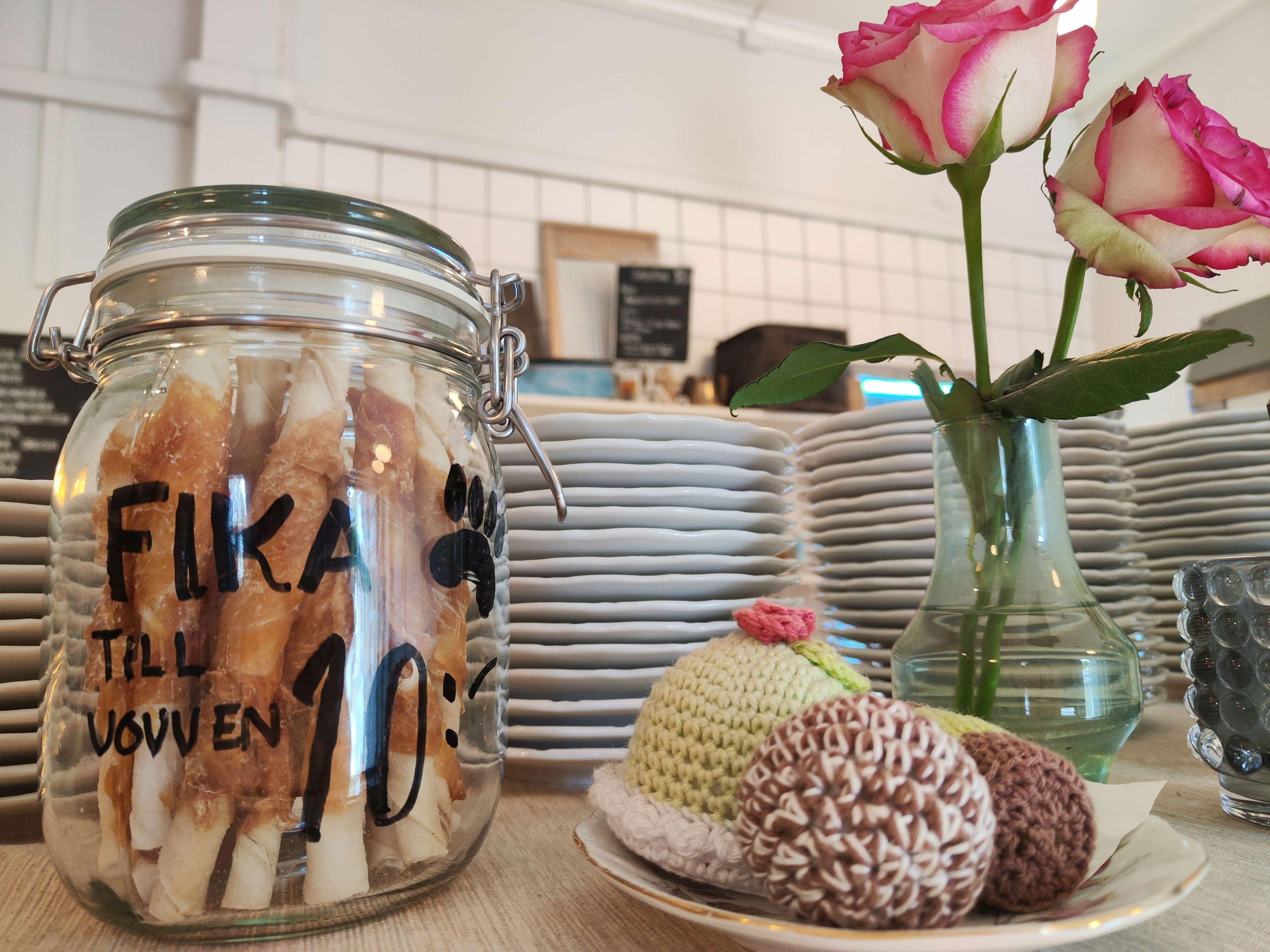 A jar filled with snacks and a vase of roses on a café table