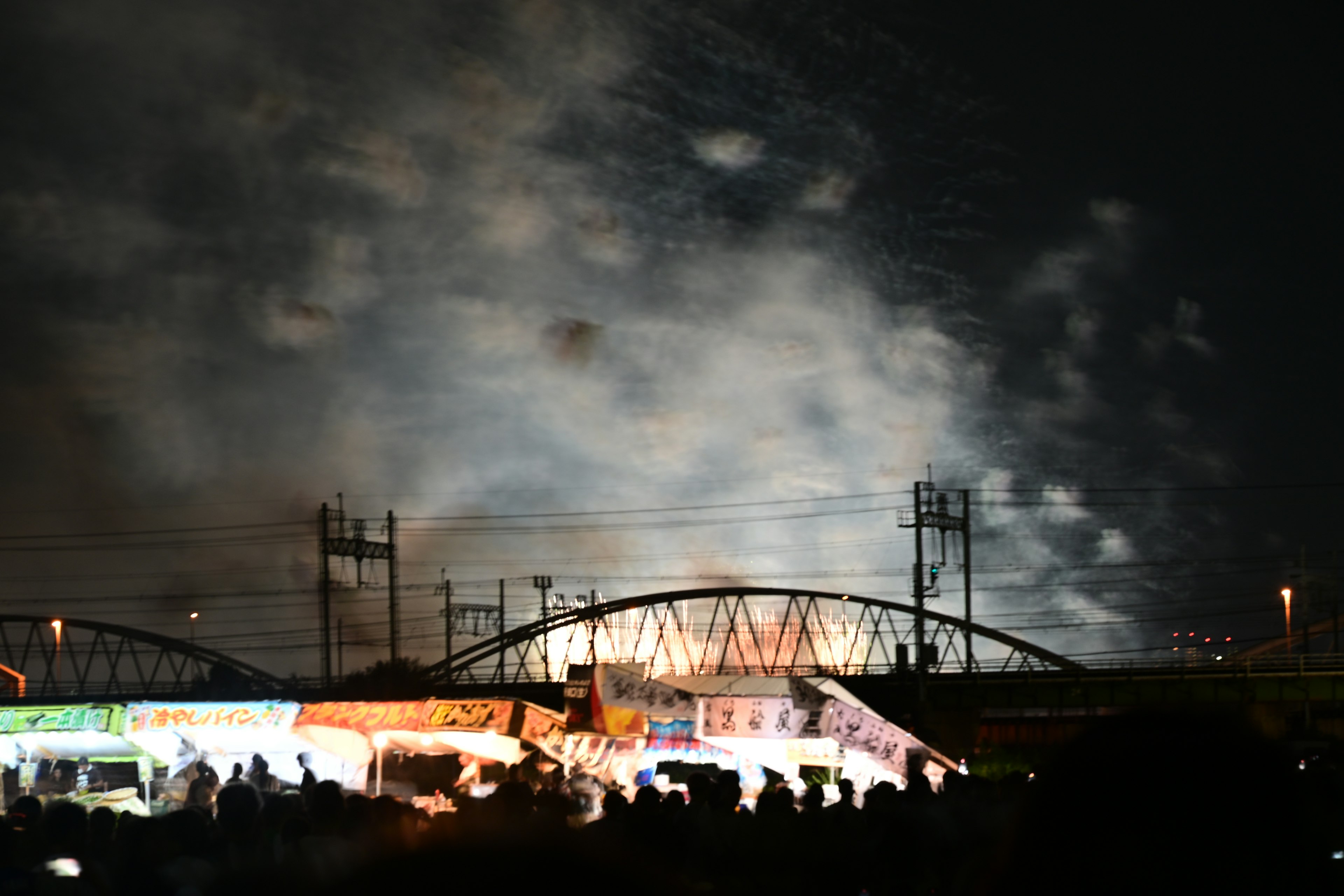 夜空に広がる花火と市場の屋台の風景