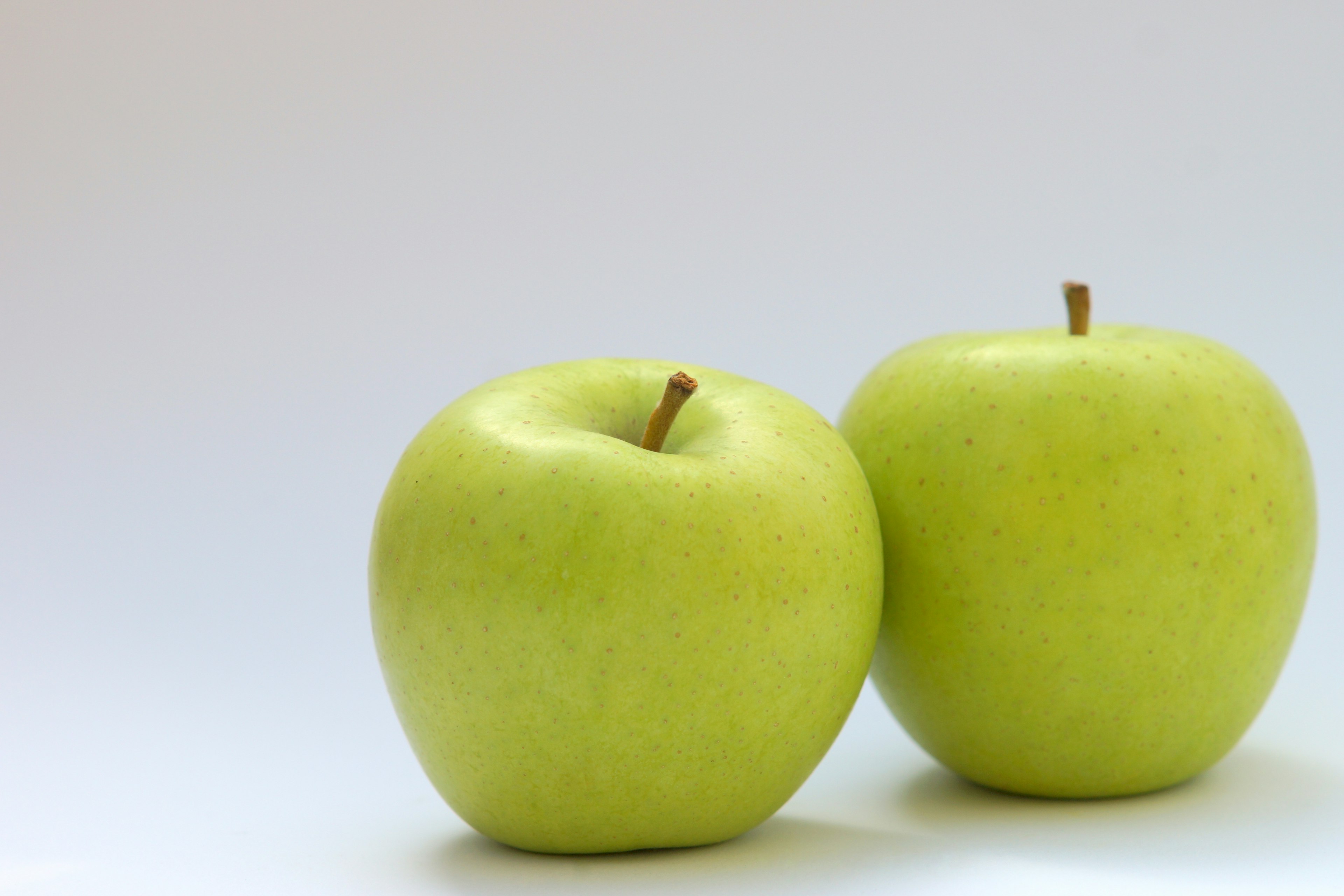 Two green apples positioned on a white background