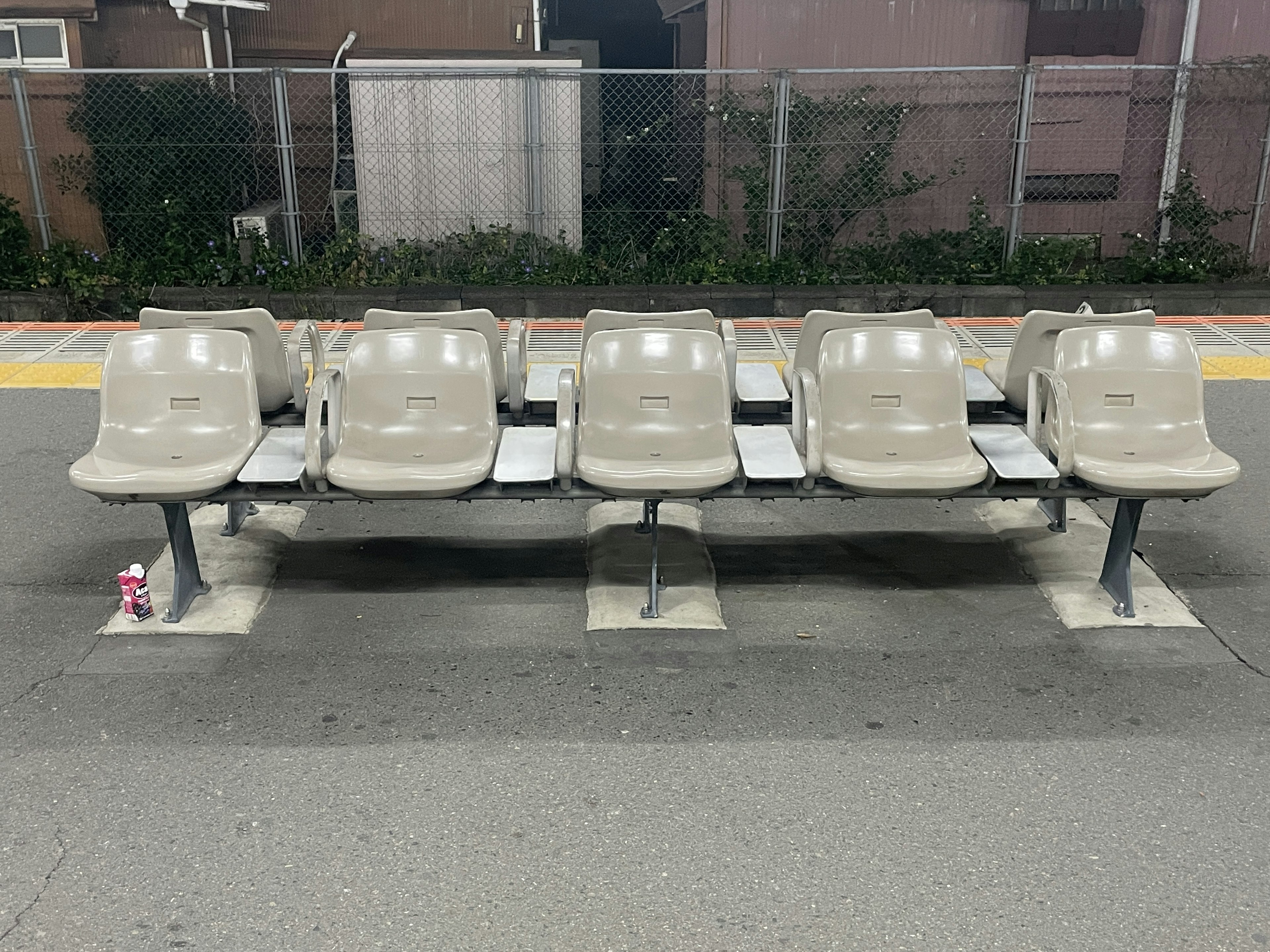 Fila de asientos beige en una estación de tren por la noche