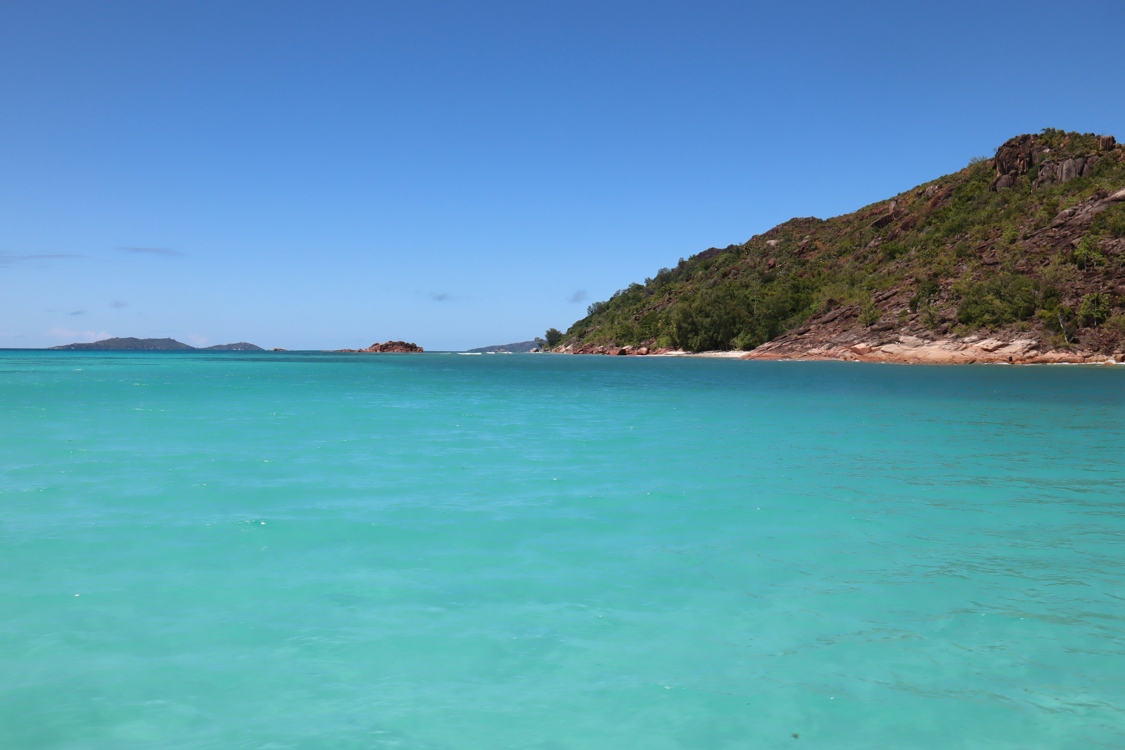 ทิวทัศน์ชายหาดที่มีน้ำสีเขียวมรกตและภูเขาสีเขียว