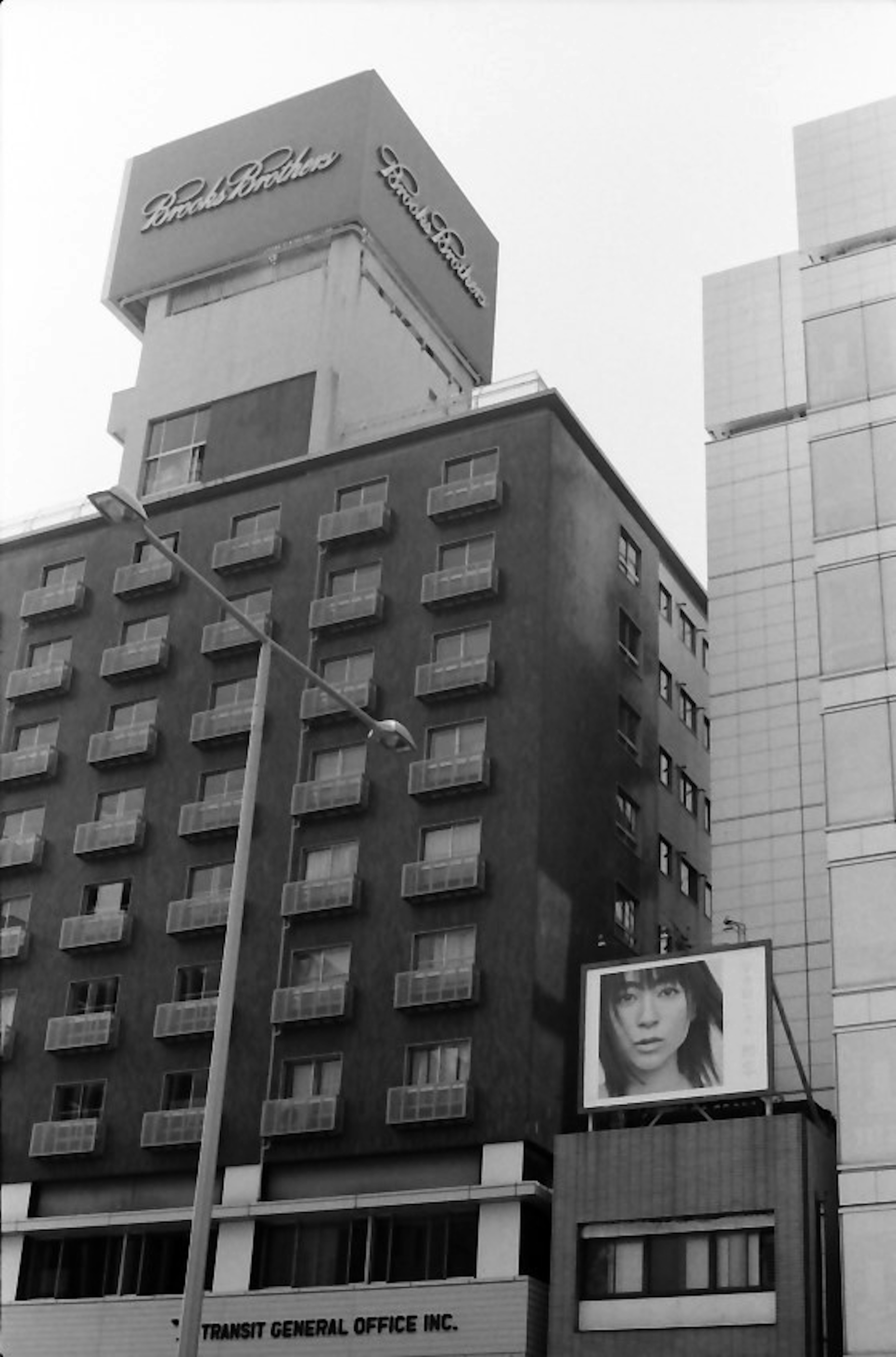 Foto in bianco e nero che mostra la facciata di un edificio e una grande pubblicità