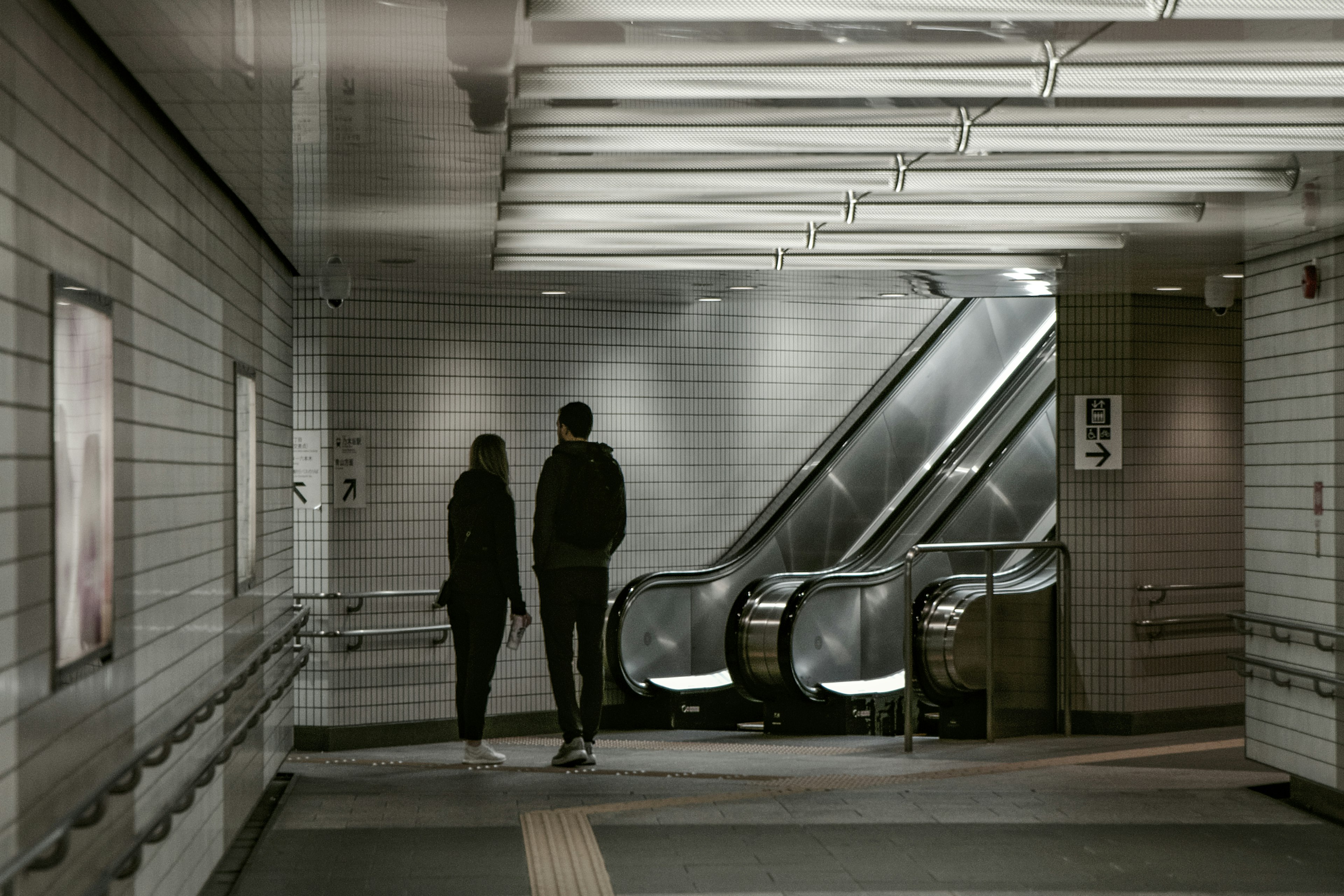 Zwei Figuren, die in einer U-Bahn-Station neben Rolltreppen gehen