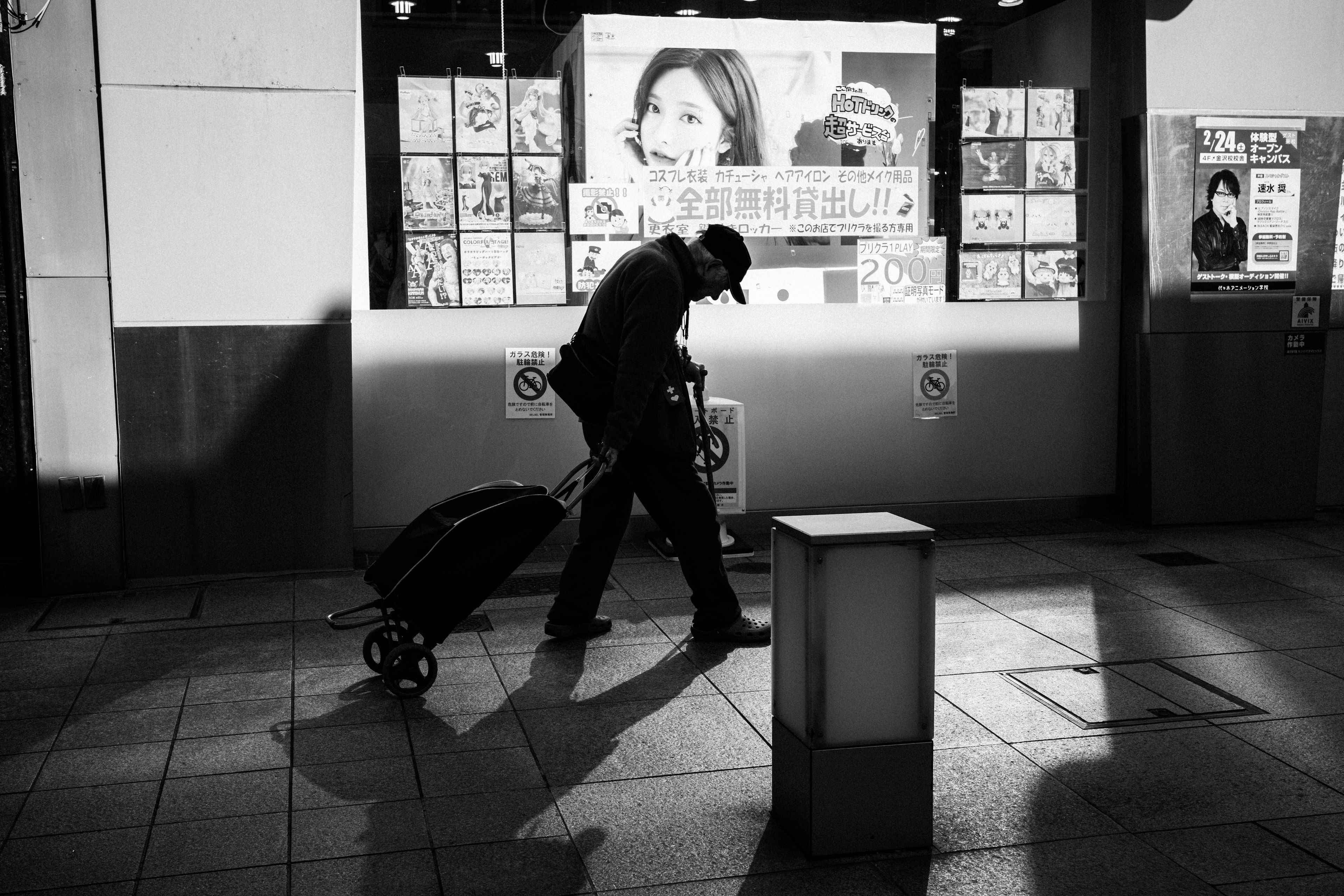 Silhouette einer Person, die einen Gepäckwagen zieht, mit Werbung im Hintergrund