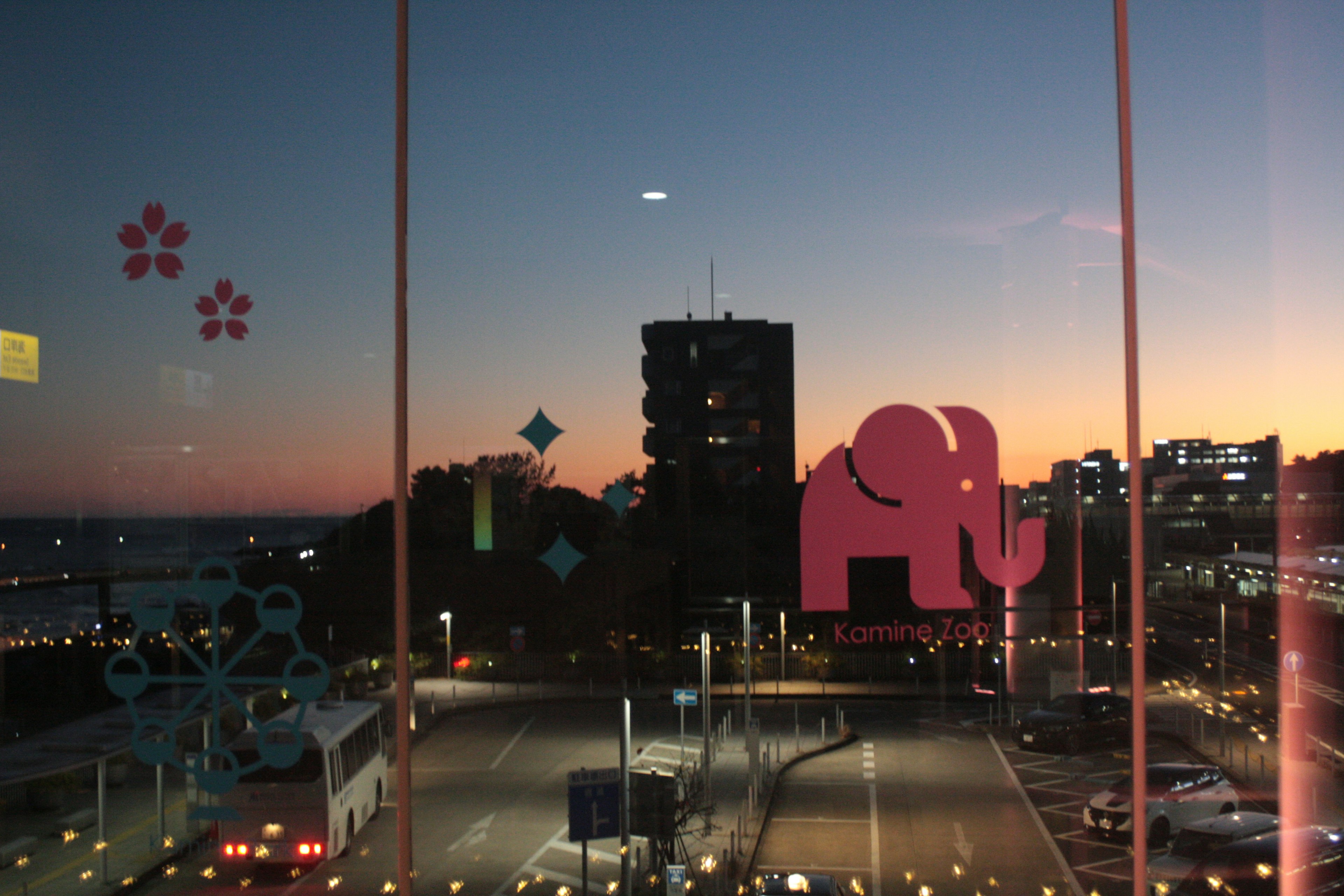 Silhouette eines Elefanten und florale Designs vor einer Stadtlandschaft bei Sonnenuntergang