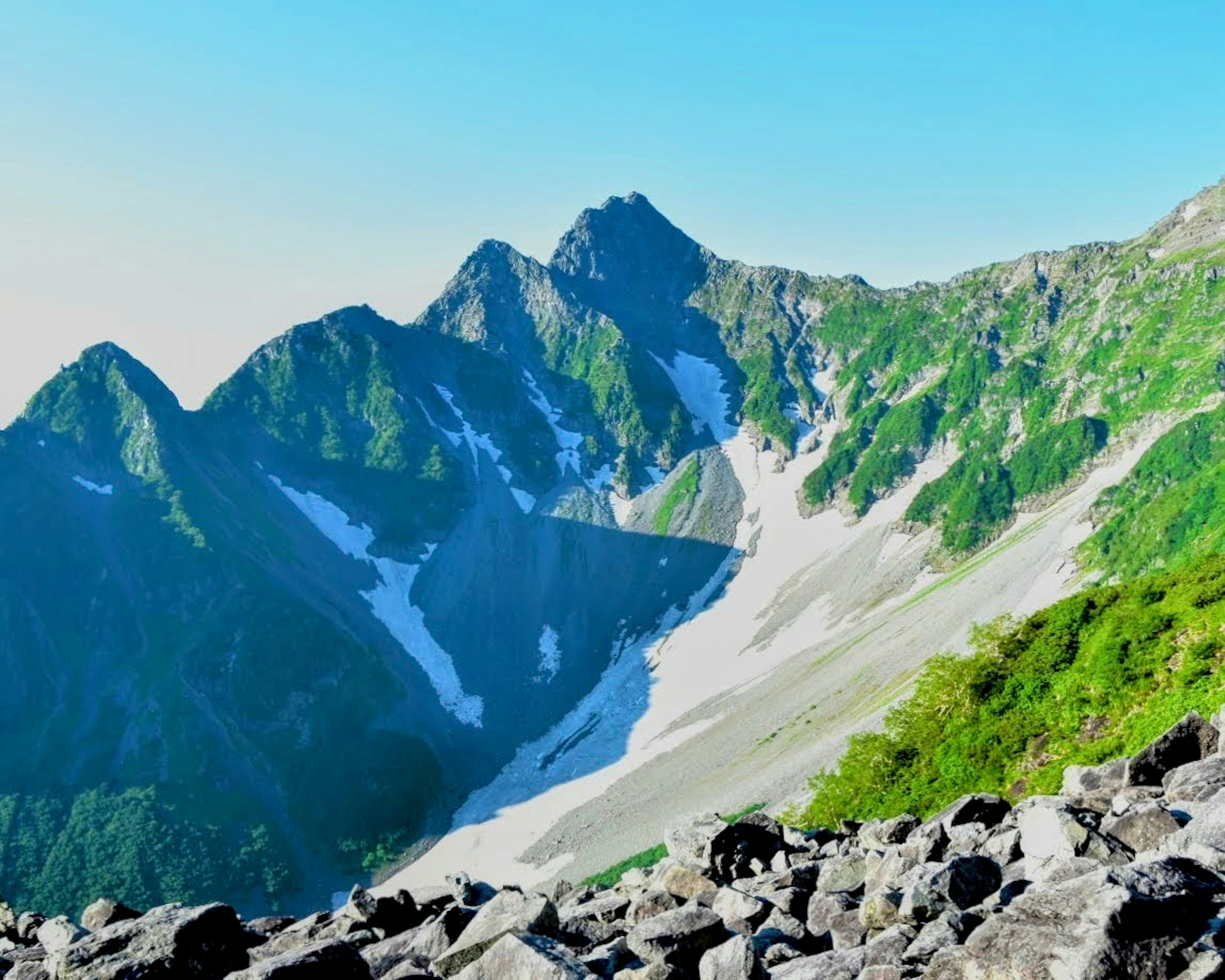 緑に覆われた山々と雪の残る斜面が広がる美しい風景