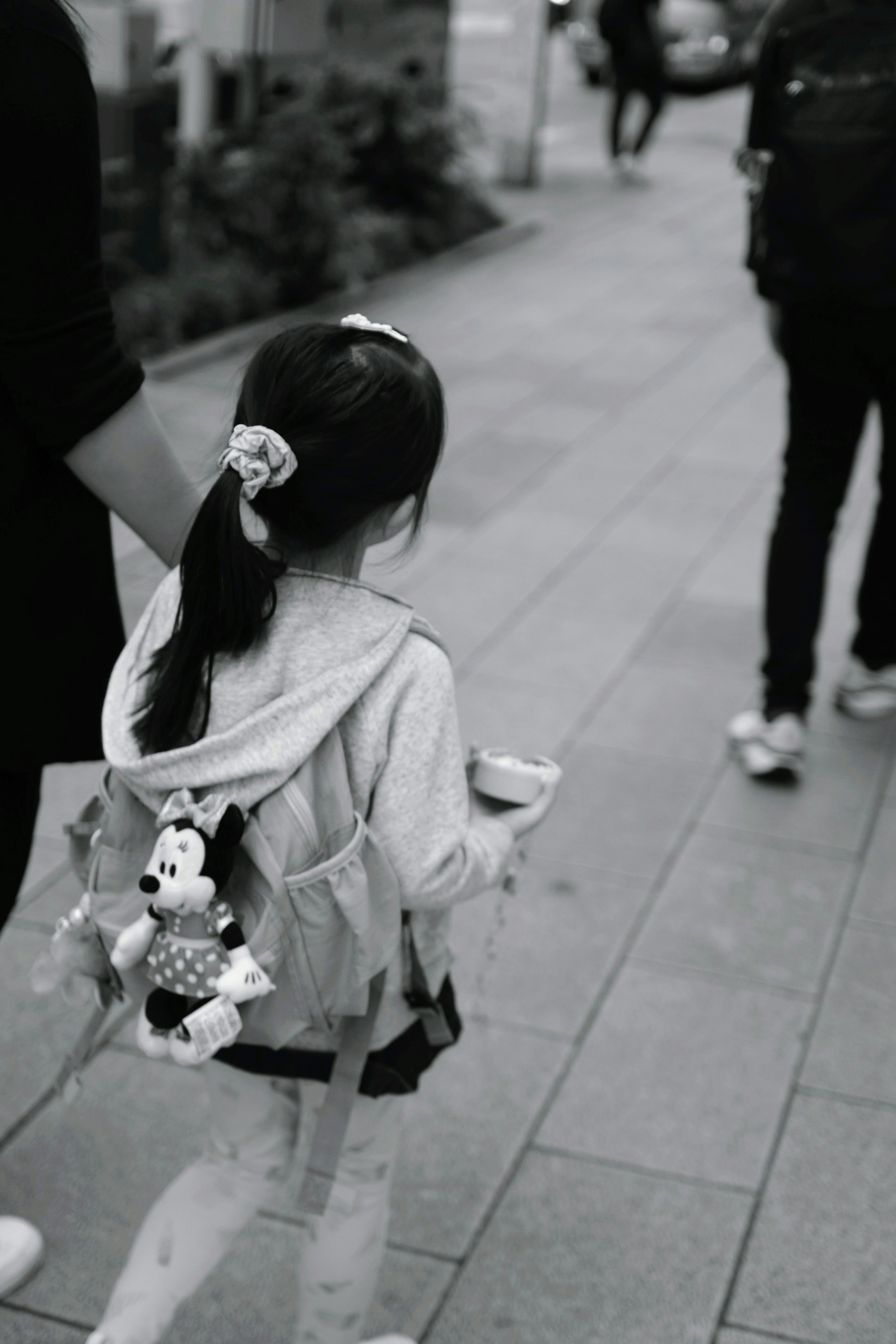 A young girl walking with a backpack featuring a stuffed toy