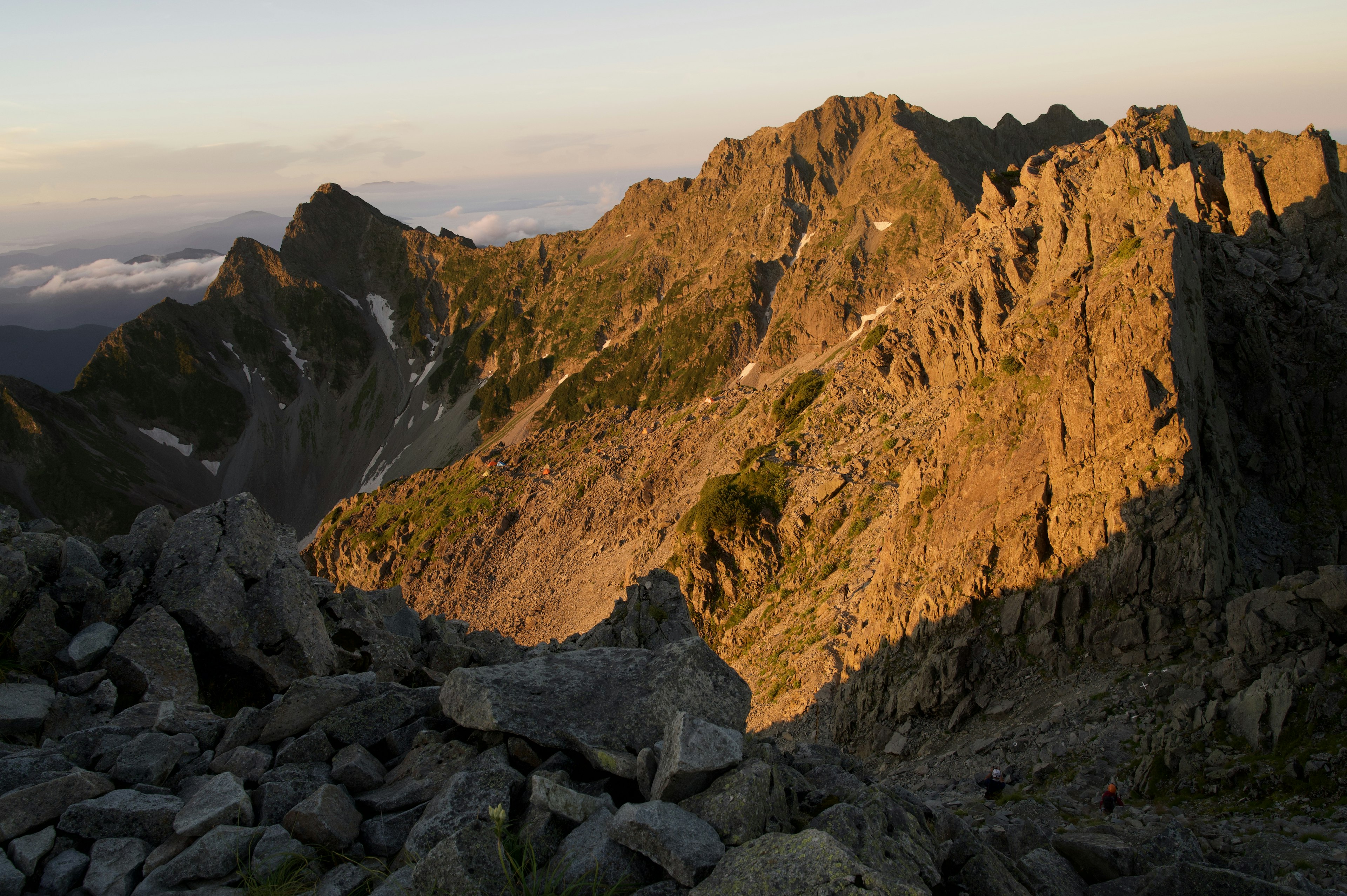 夕日が照らす山の風景で岩と緑が見える