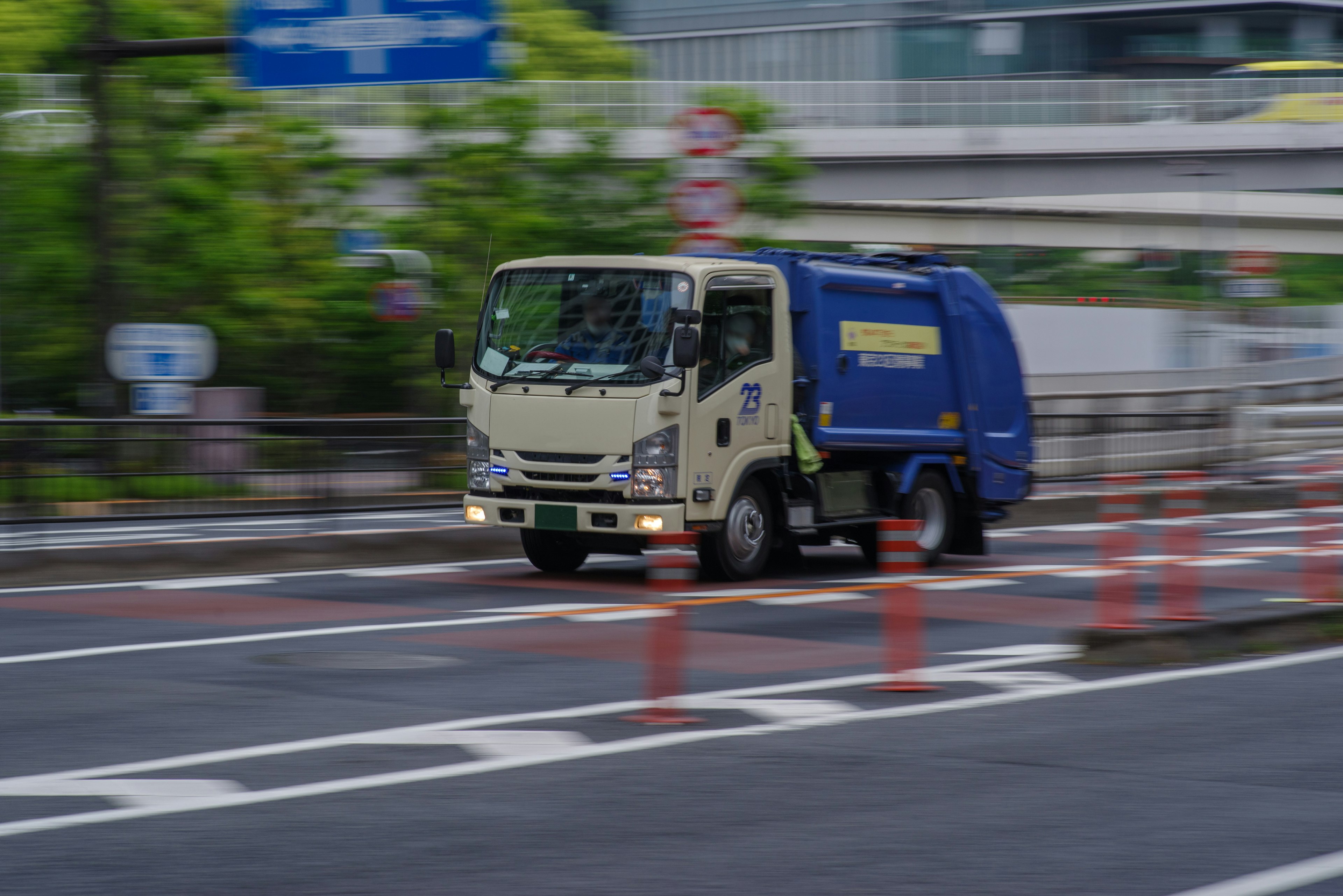 Un camion della spazzatura blu che guida su una strada urbana