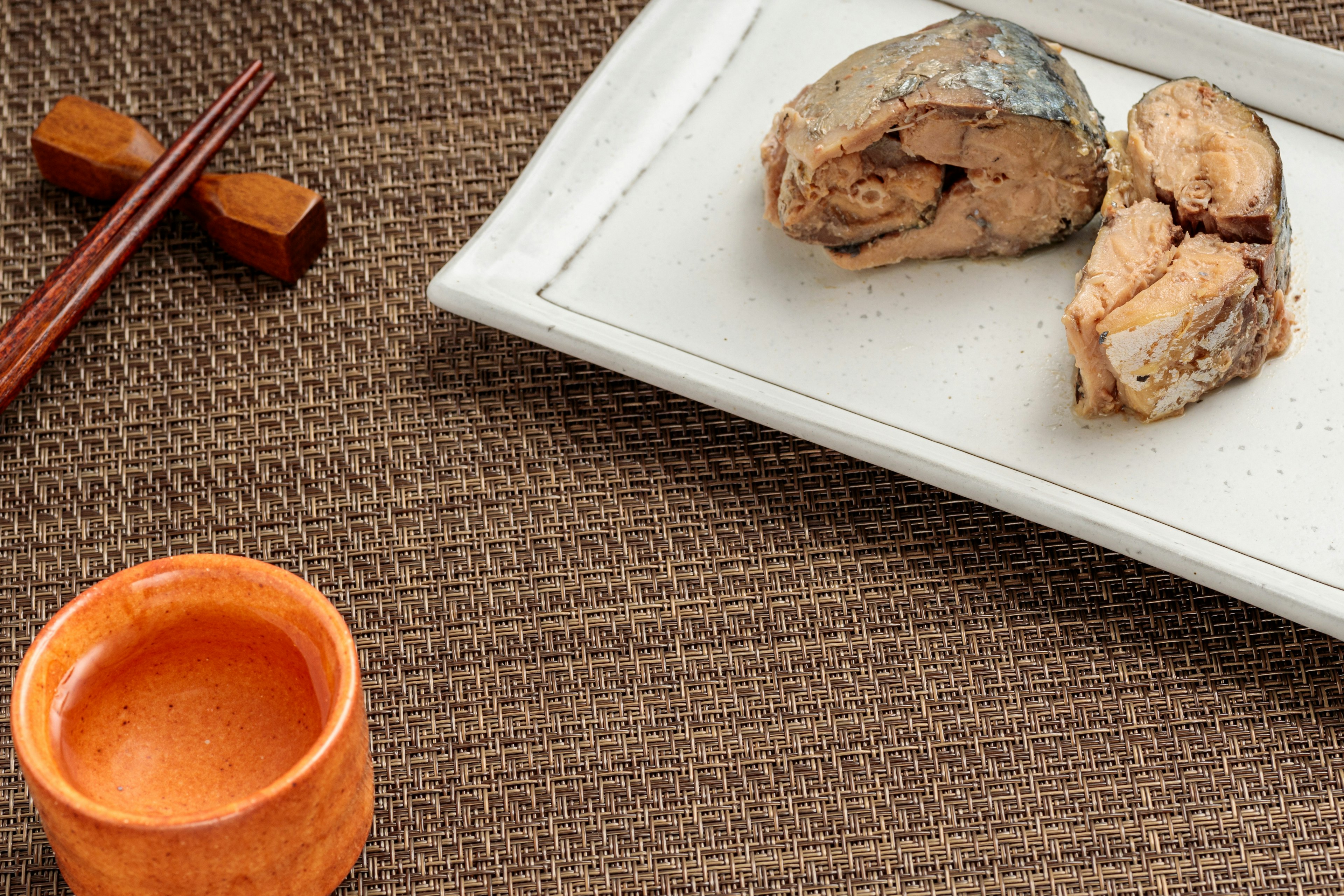 Filetti di pesce su un piatto bianco con una piccola tazza arancione