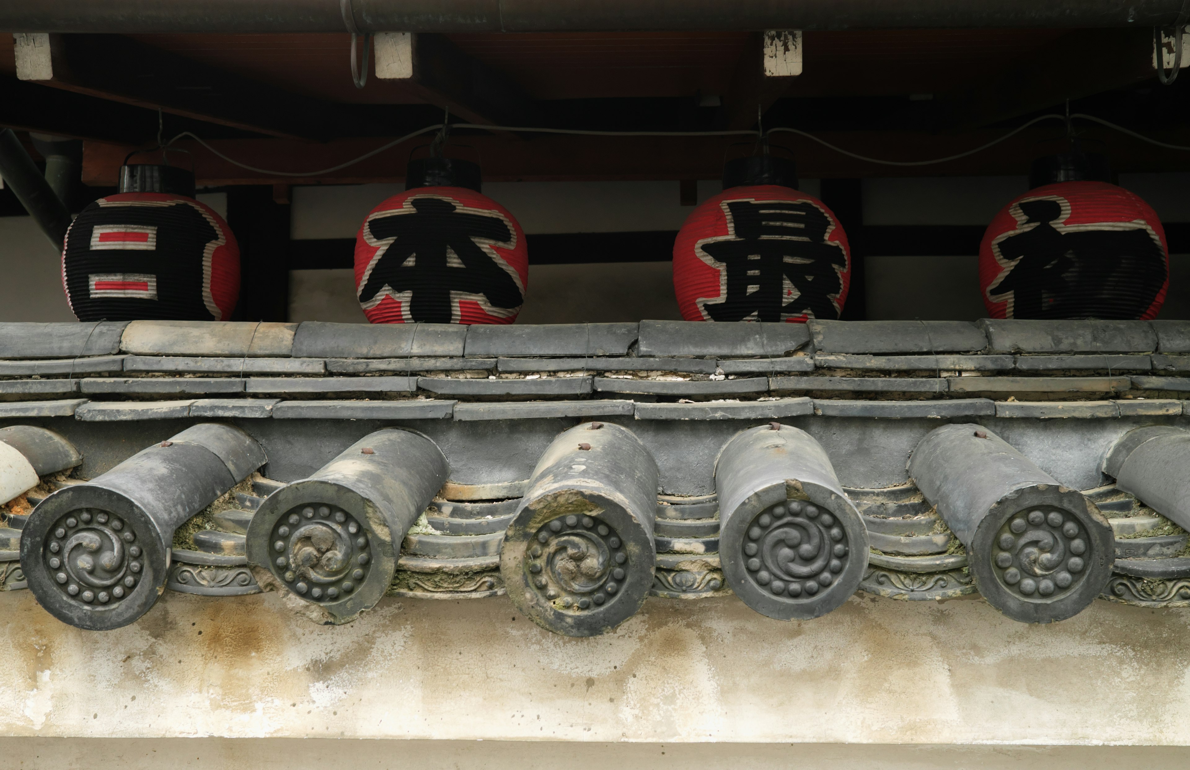 Traditional Japanese roof tiles with decorative red lanterns above