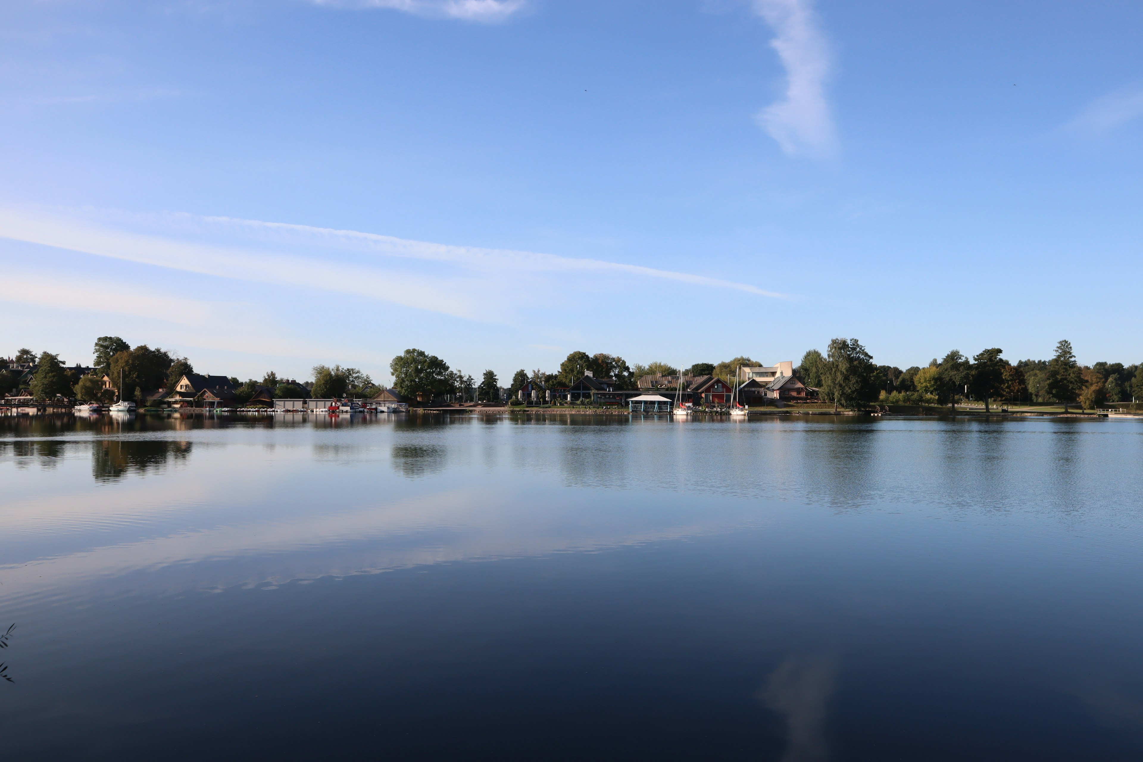 Vista serena del lago reflejando casas y cielo azul