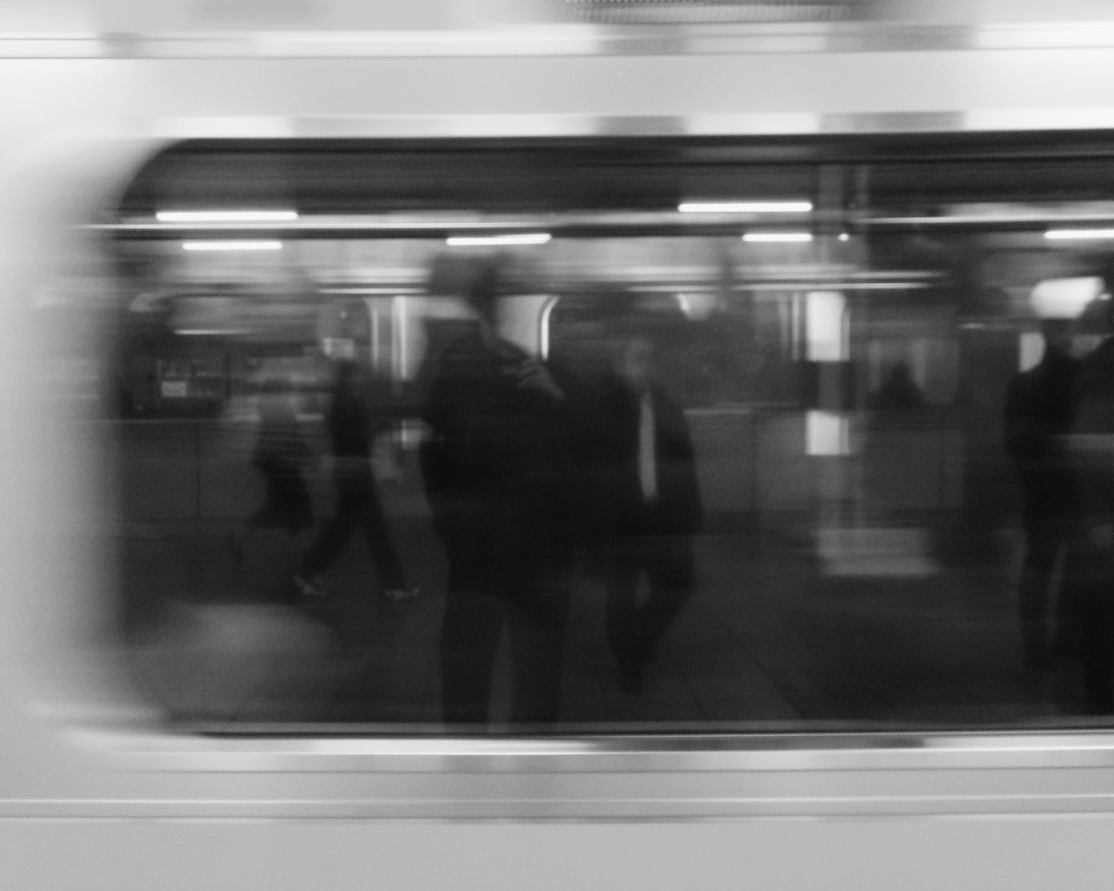 Siluetas borrosas de personas vistas a través de una ventana de tren en blanco y negro