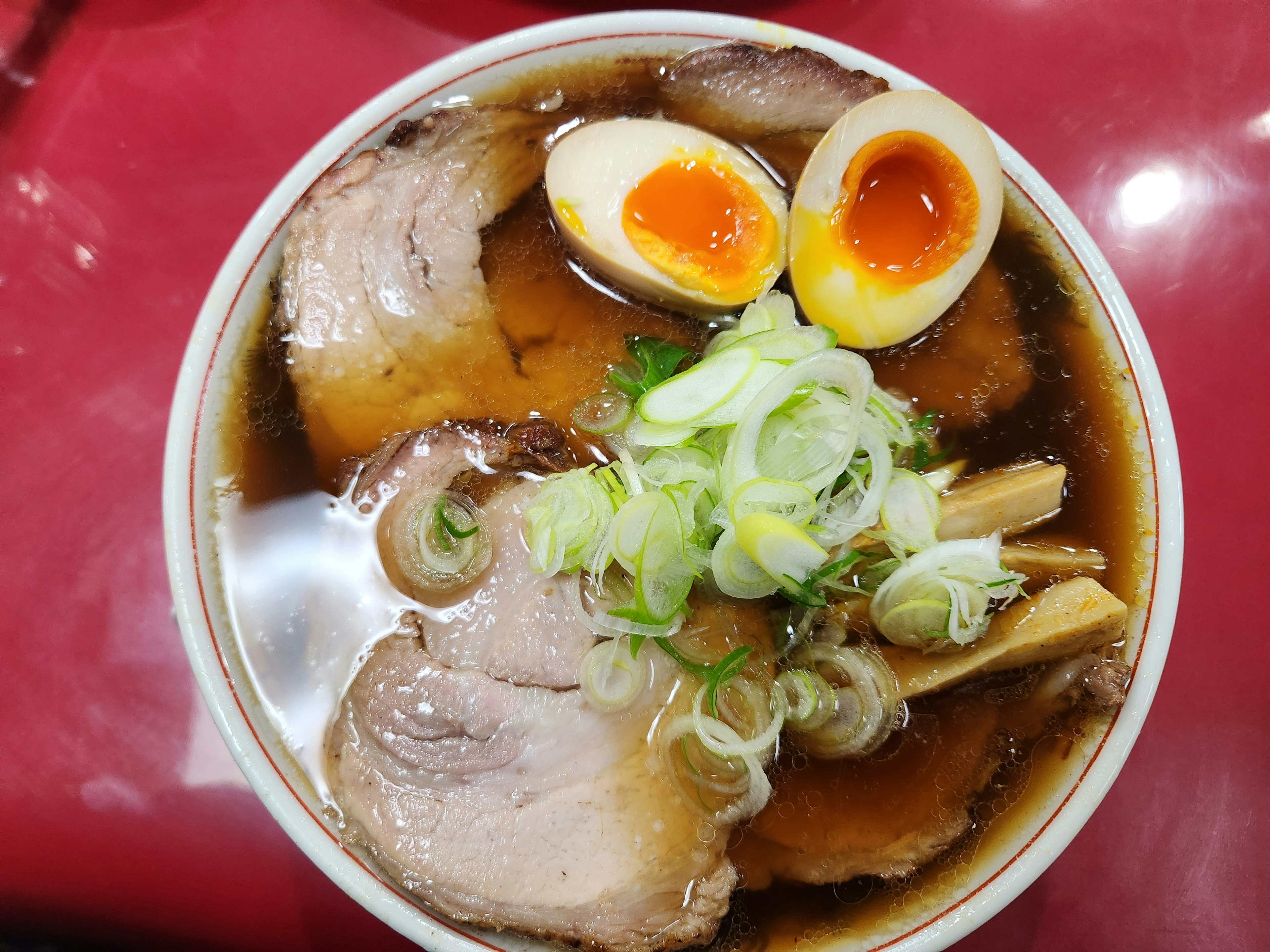 ラーメンのボウルにチャーシューと煮卵がトッピングされている