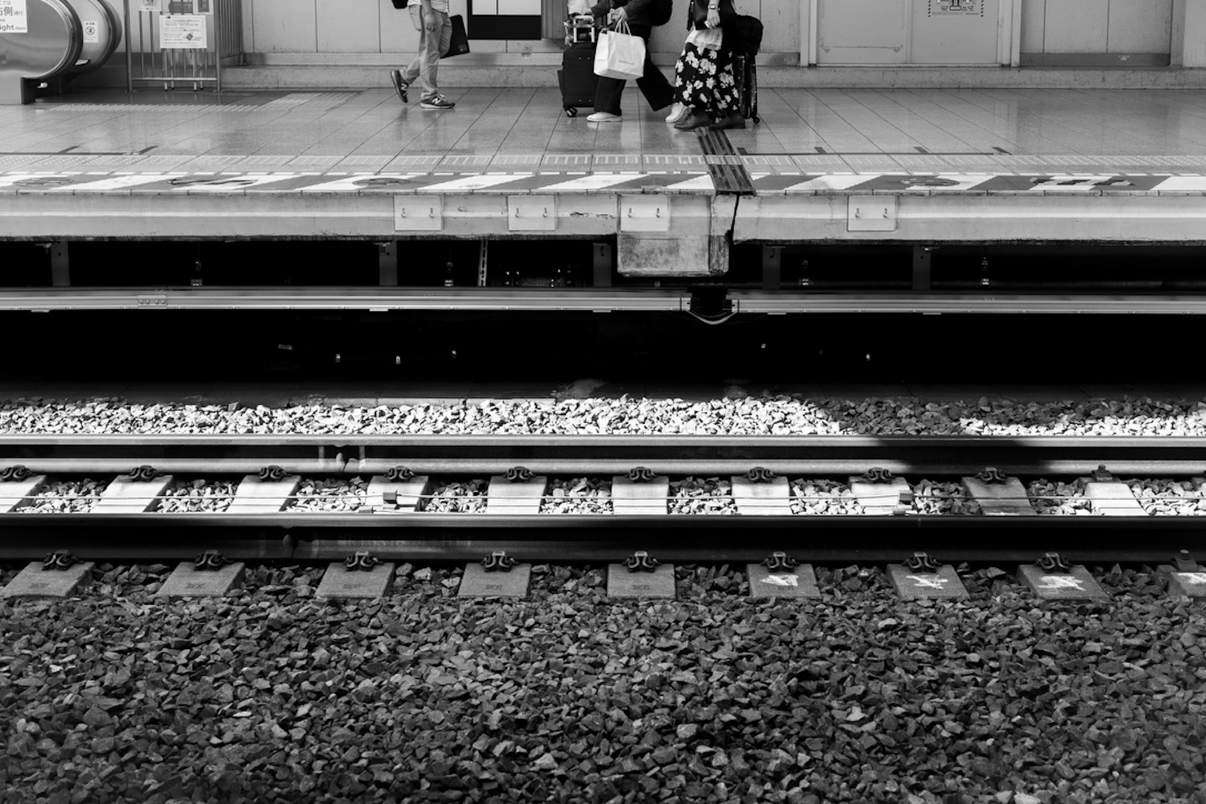 Image en noir et blanc d'une plateforme de gare et de voies ferrées