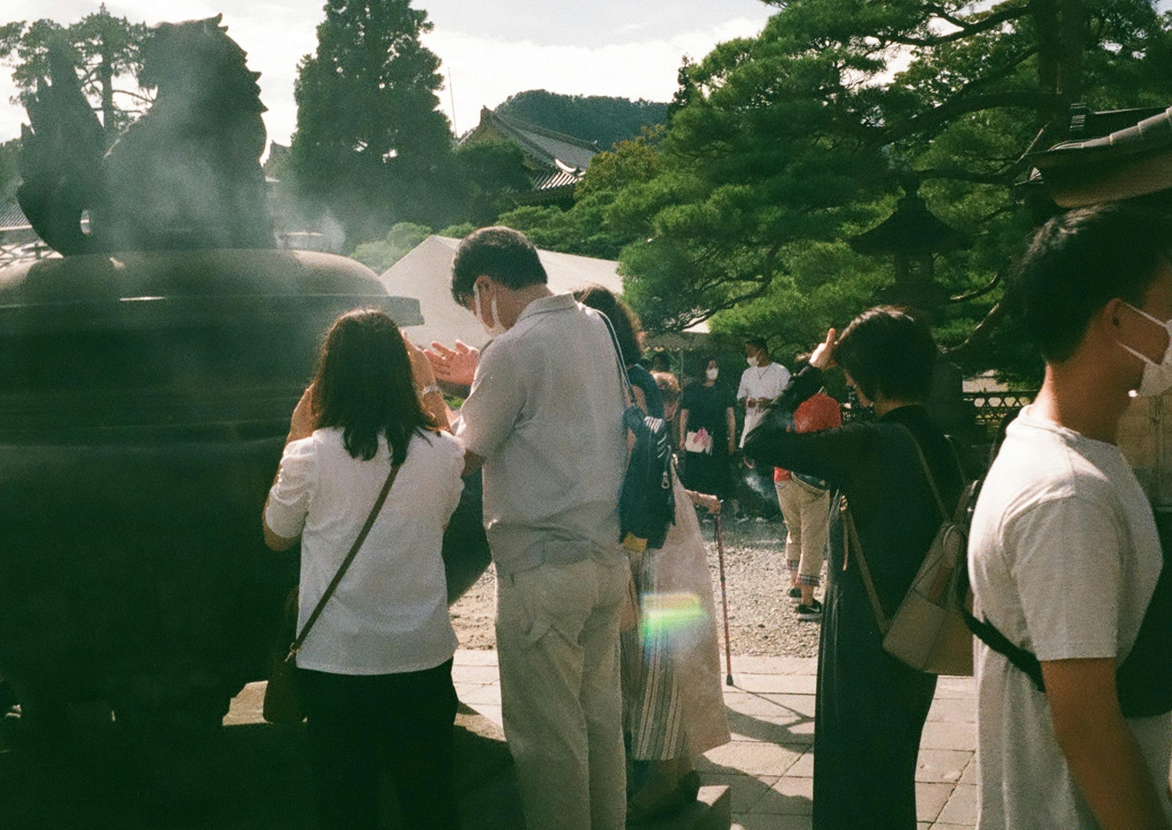 人々が香炉の前で祈りを捧げている風景 緑豊かな背景