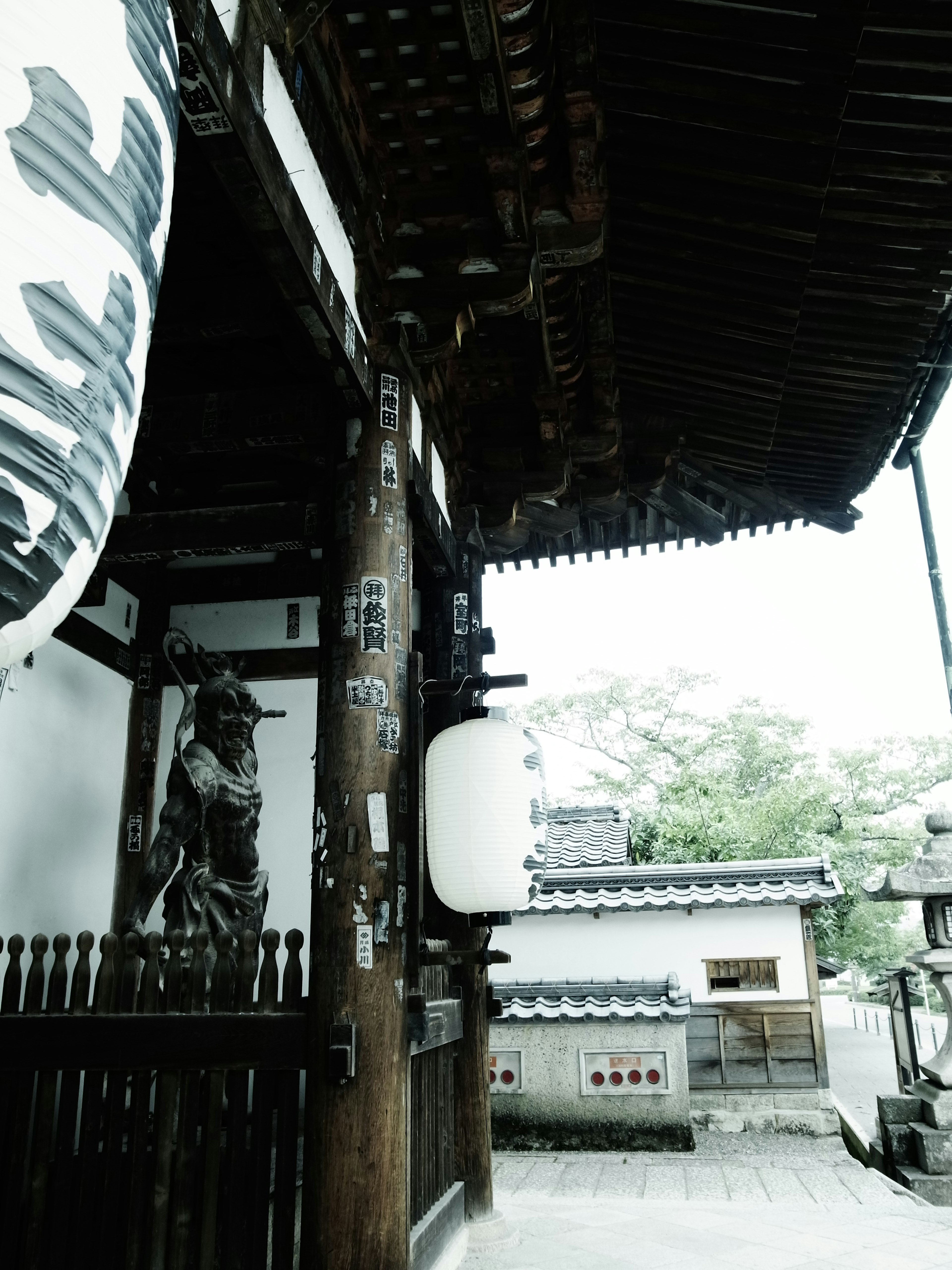 Vista de una antigua puerta de templo japonés con una linterna