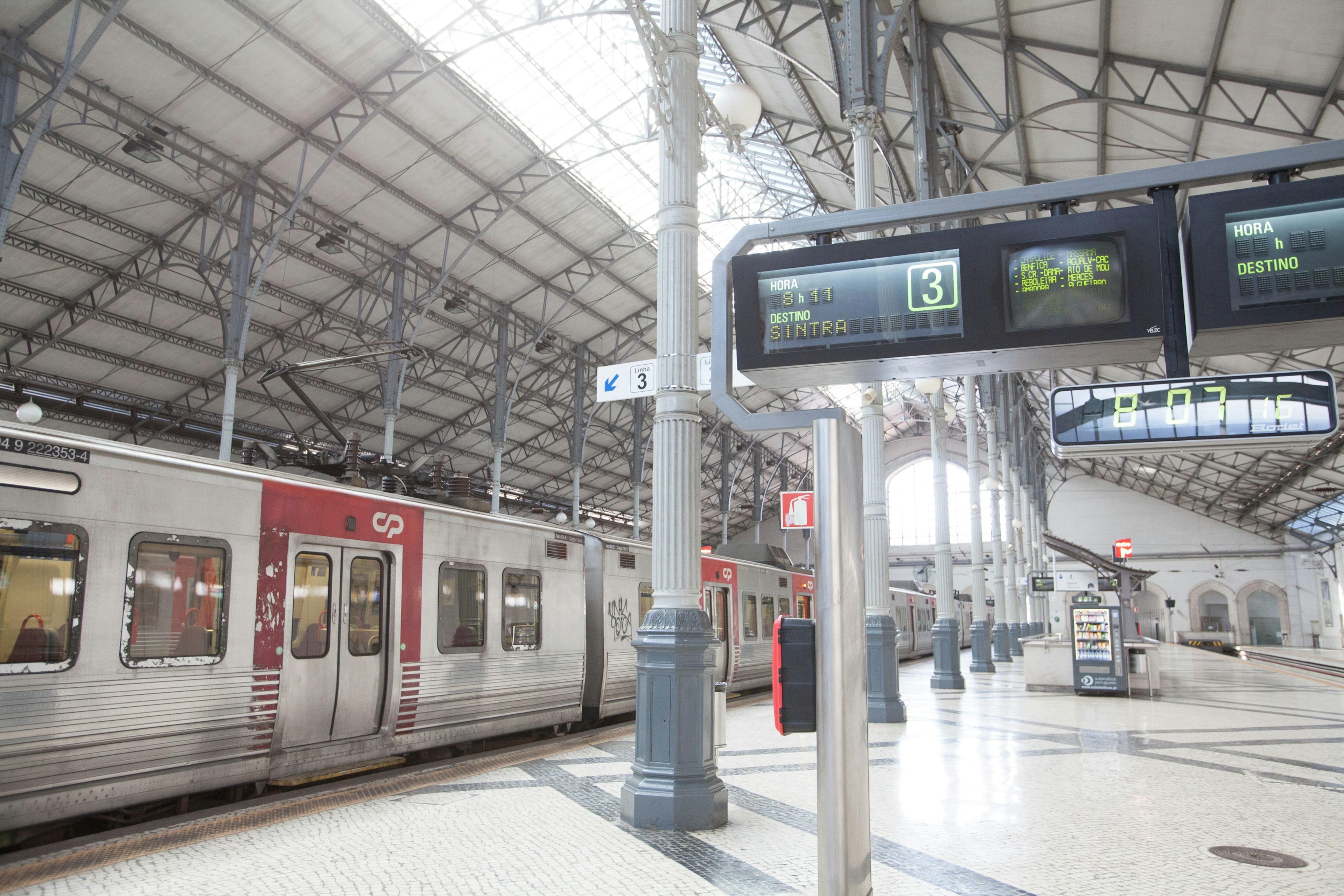 Interior de una estación de tren iluminada con un tren y una pantalla digital