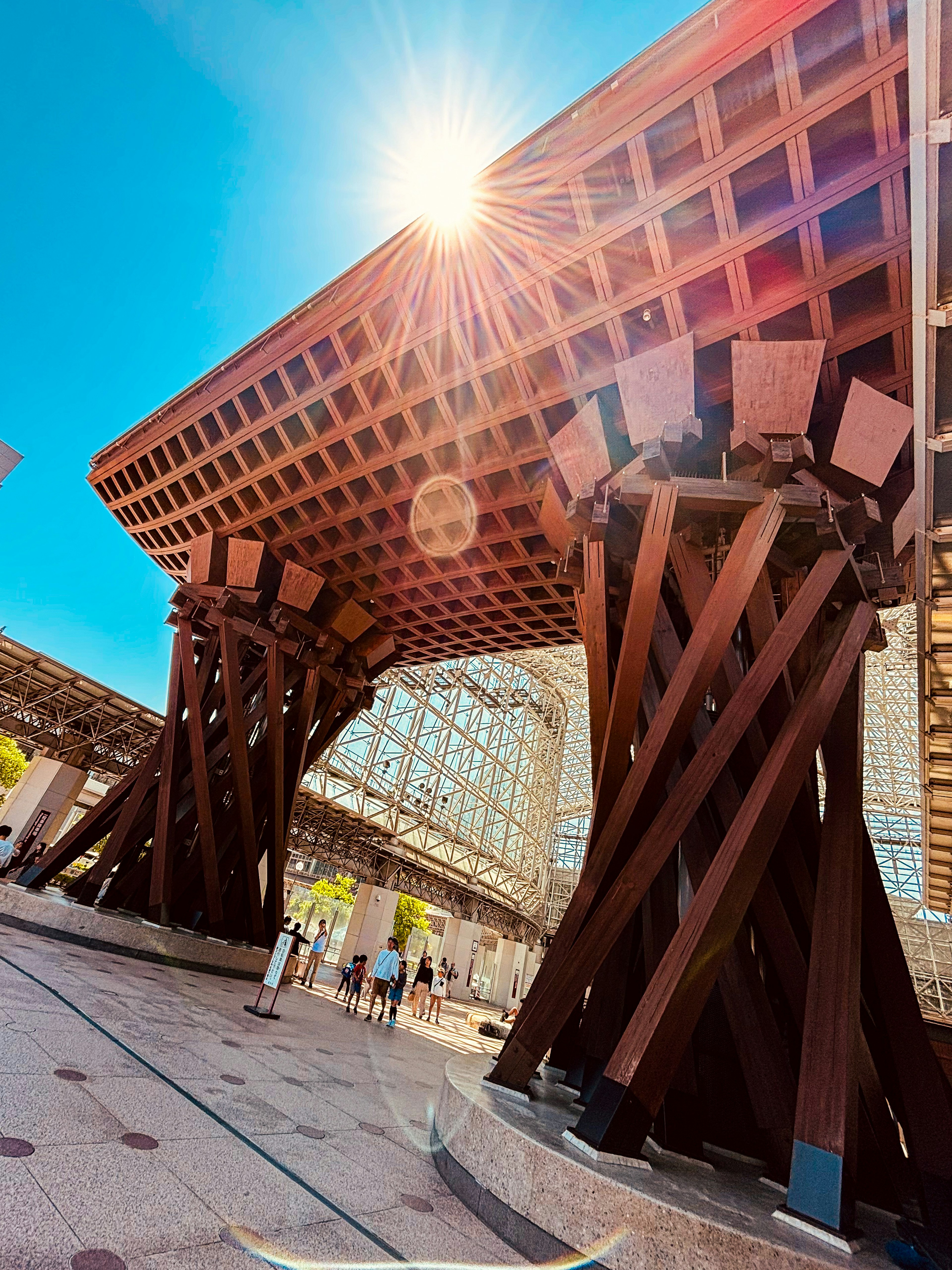 Modern architecture featuring large wooden pillars and bright sunlight