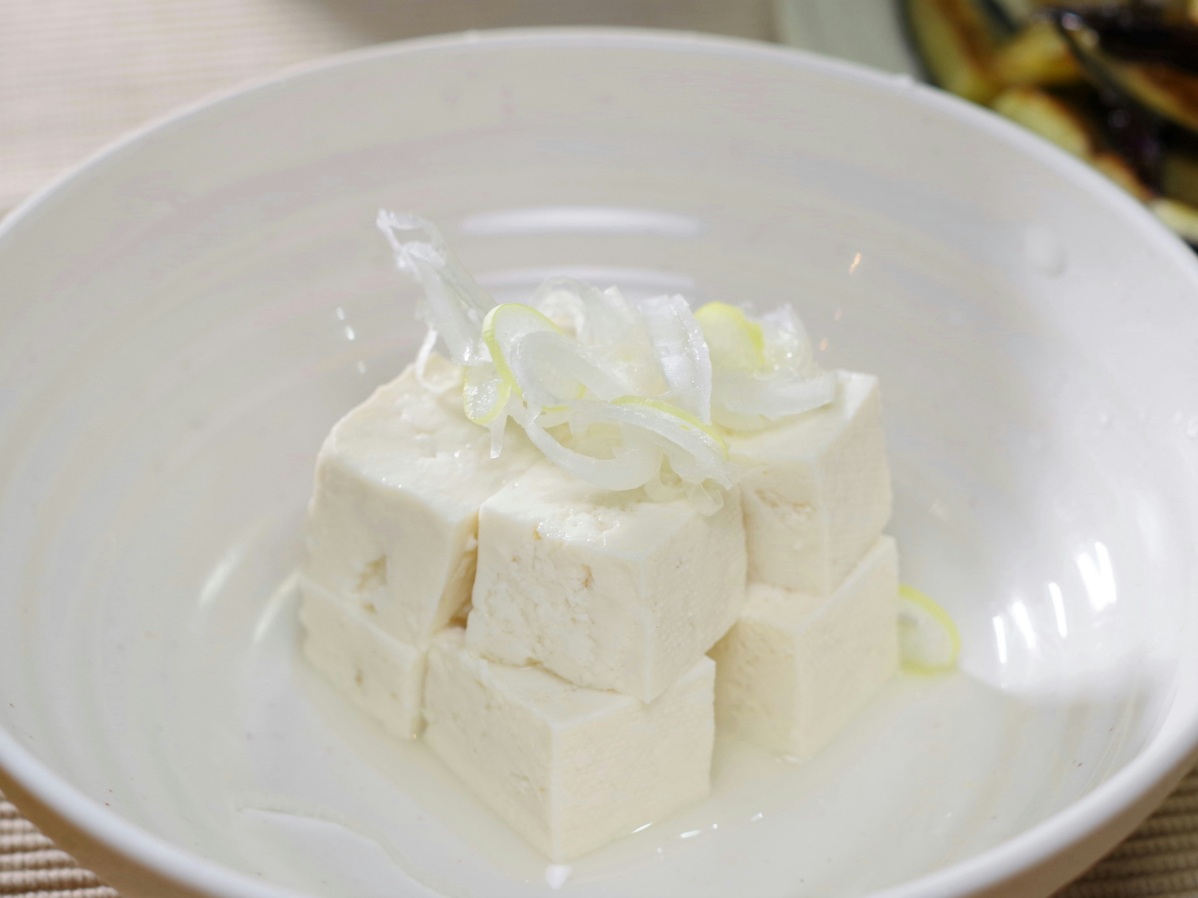 Tofu en cubos con cebollino en rodajas en un tazón blanco