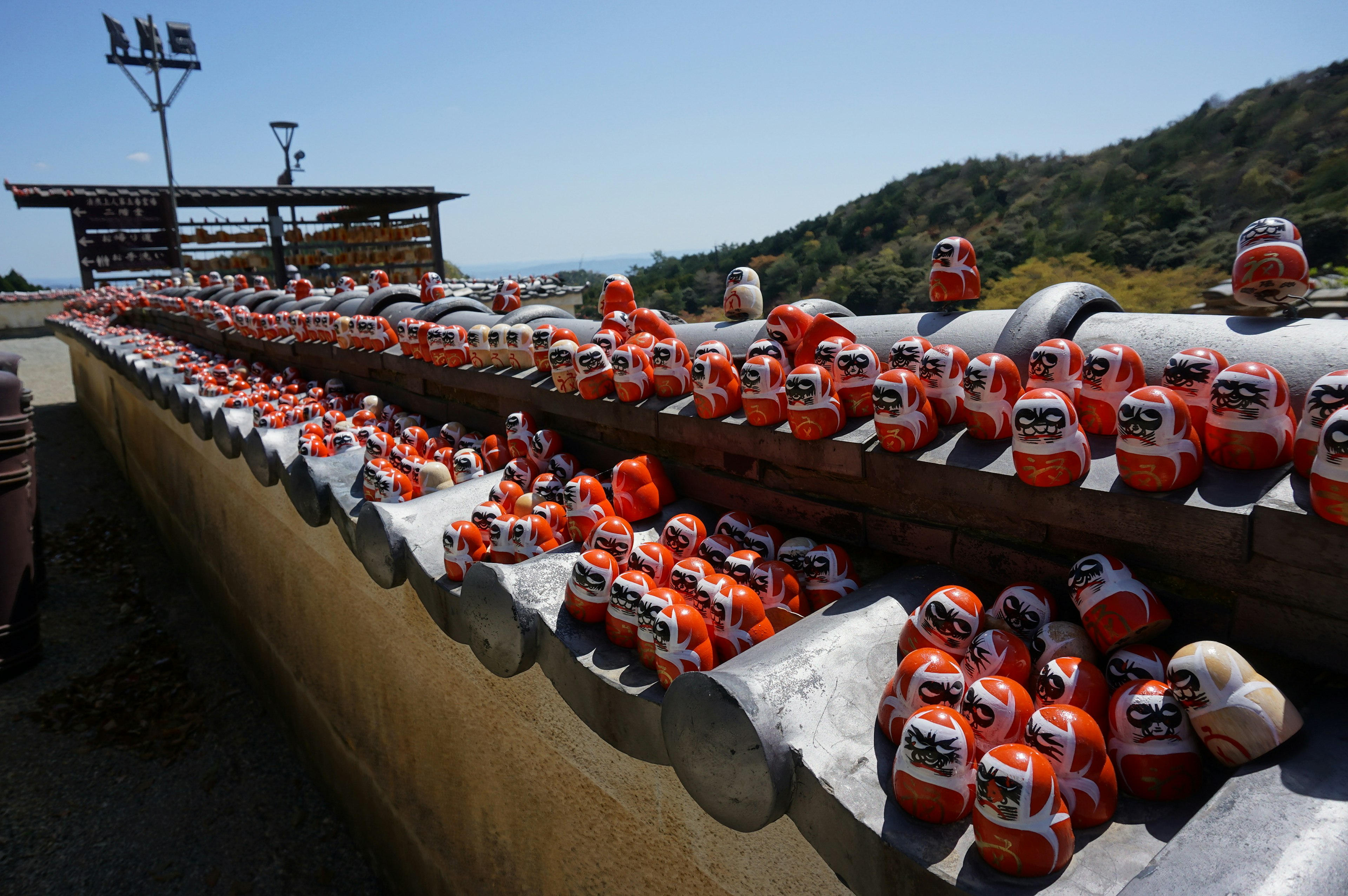 Pemandangan dengan banyak boneka daruma merah yang disusun di atap