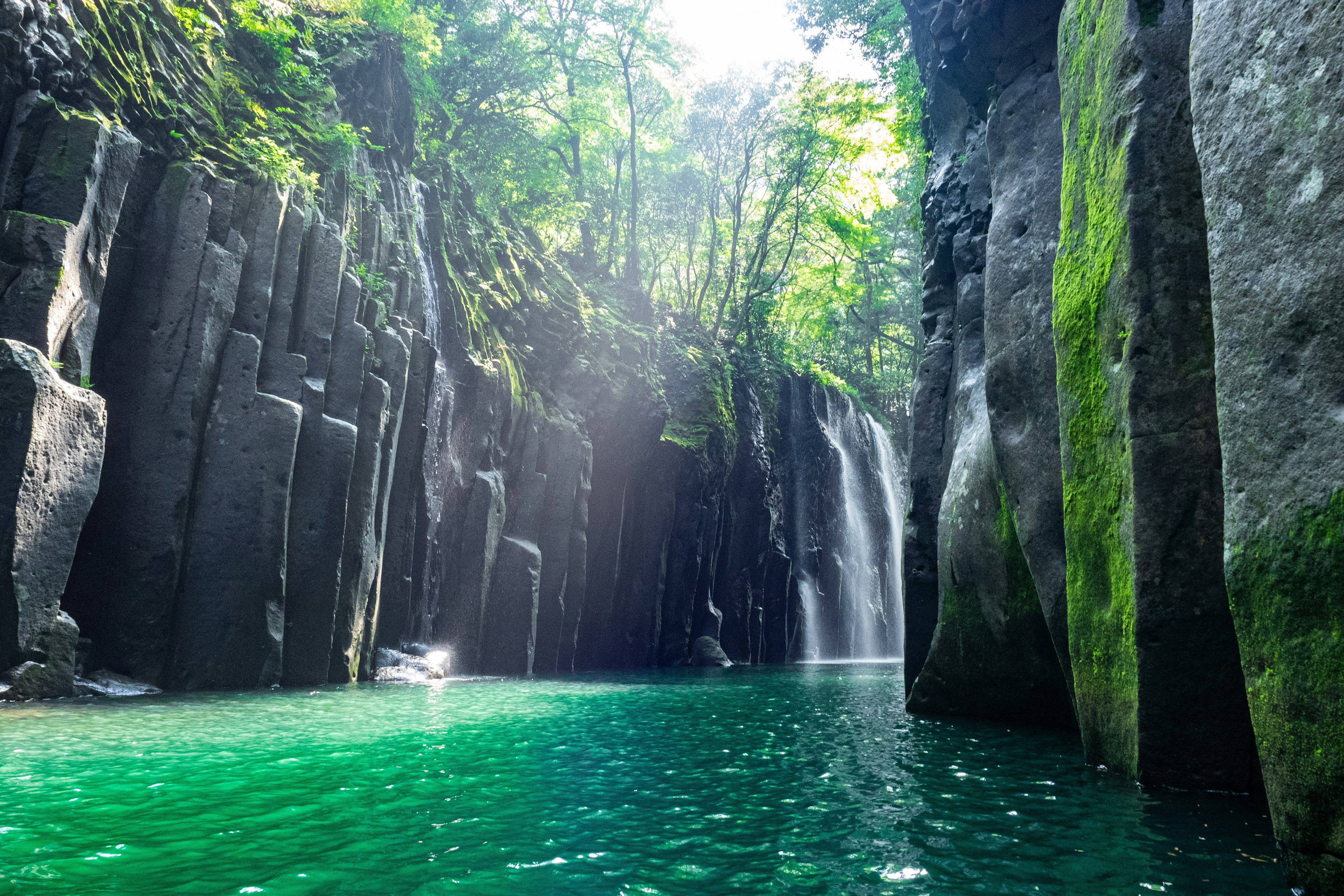 Beeindruckender Wasserfall umgeben von üppigem Grün und türkisfarbenem Wasser