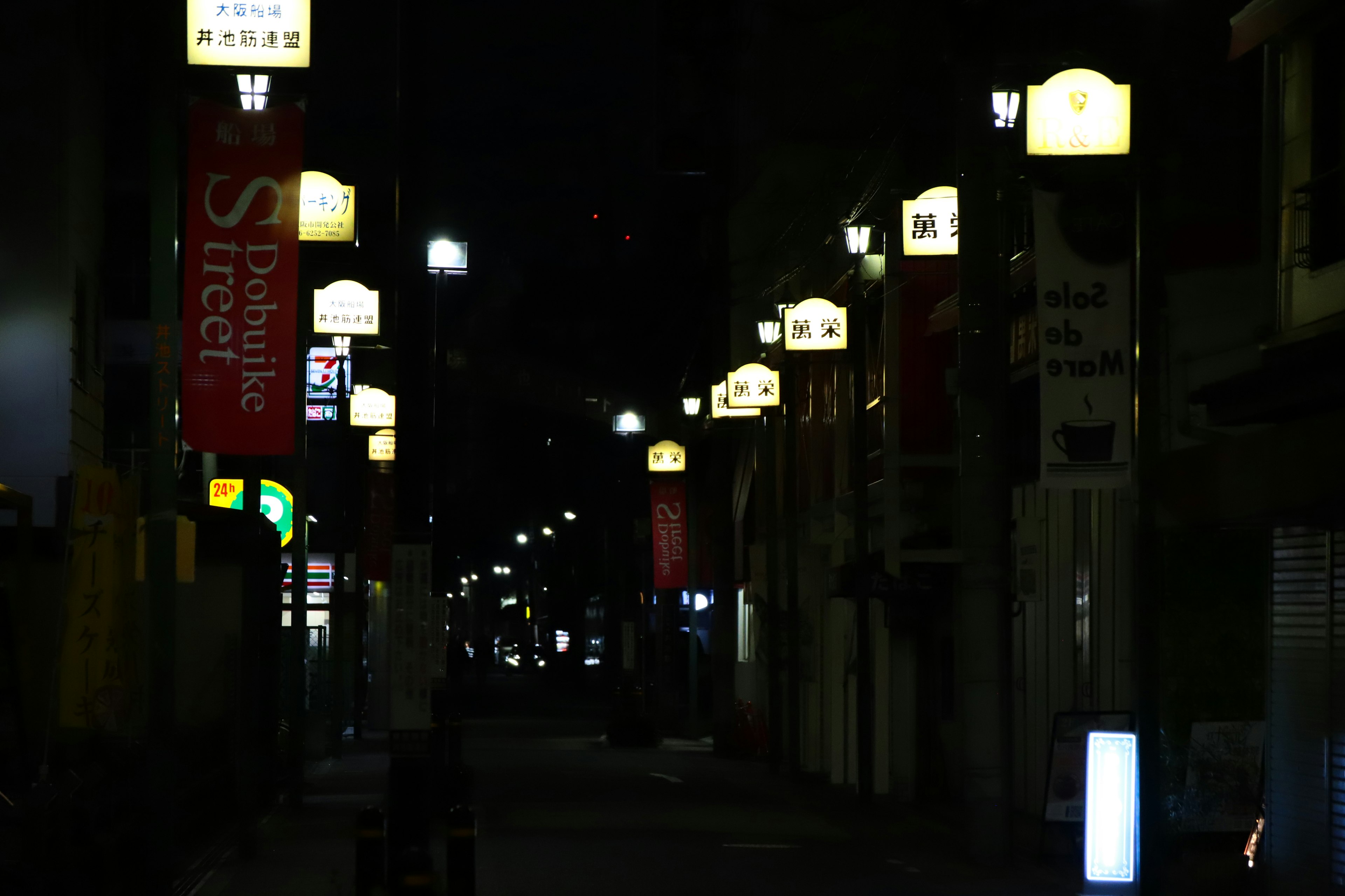 Illuminated street lamps and signs in a nighttime urban setting