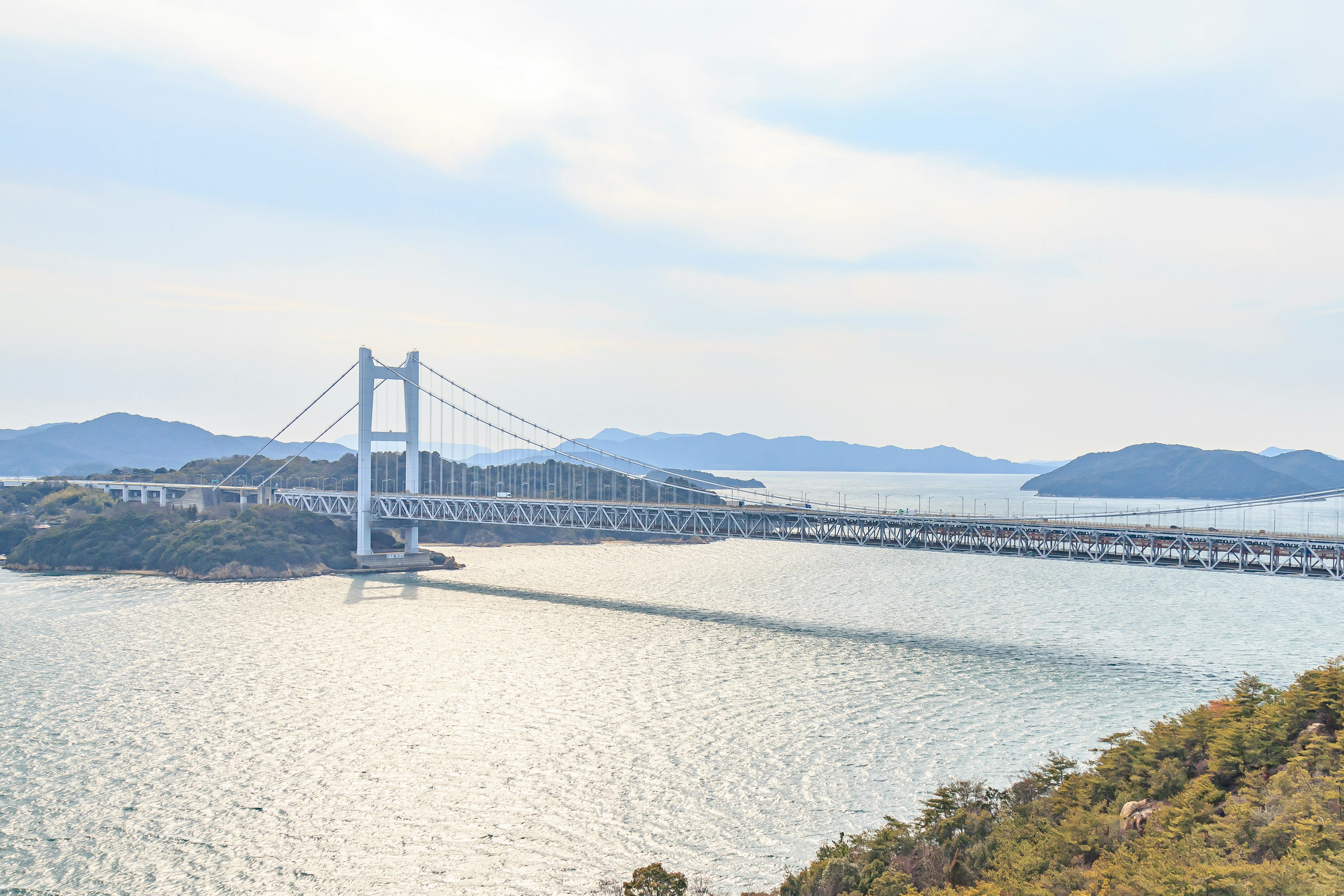 สะพานที่มีทิวทัศน์ทอดยาวข้ามน้ำที่สงบพร้อมเกาะห่างไกล