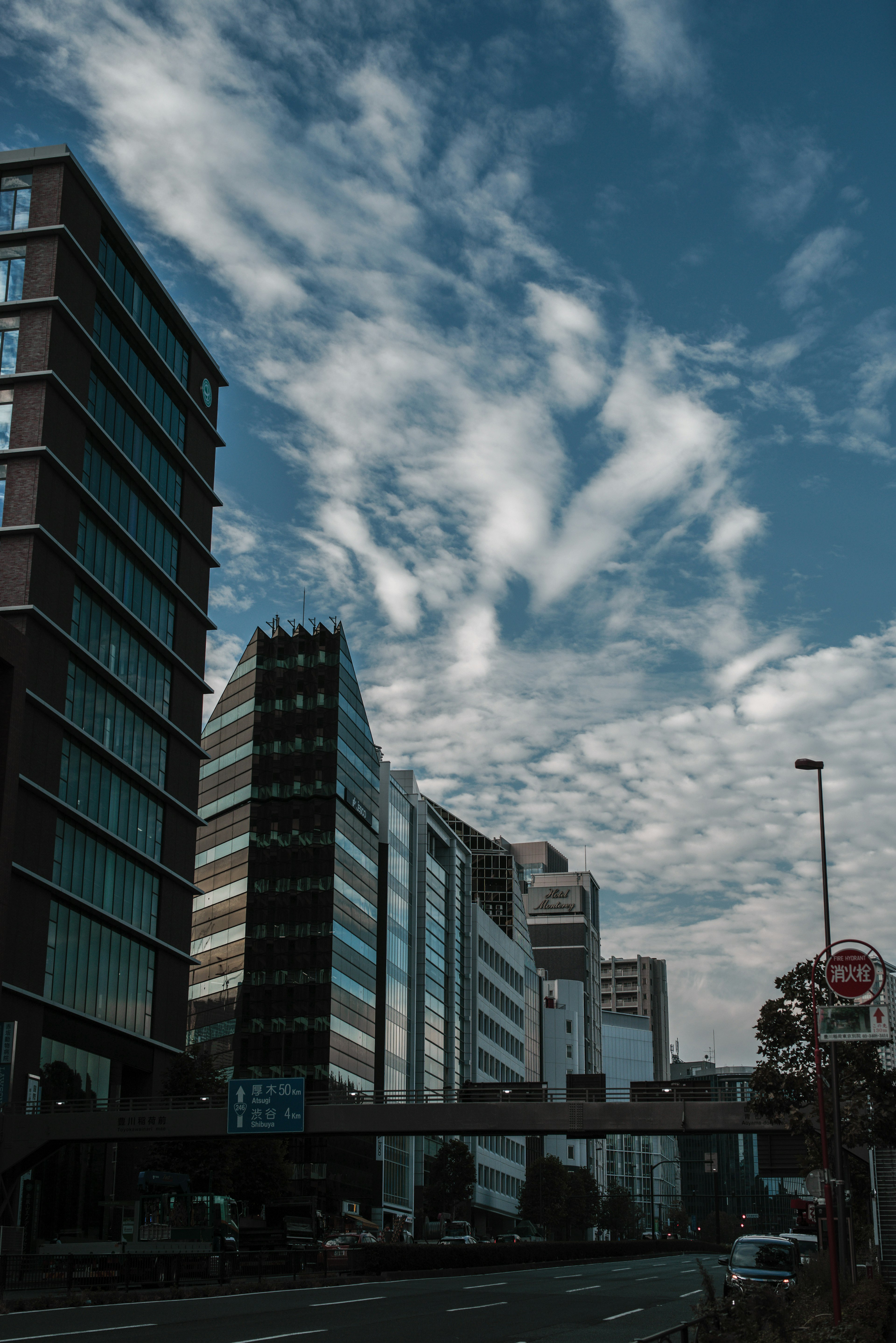 Cityscape featuring tall buildings under a blue sky with scattered clouds