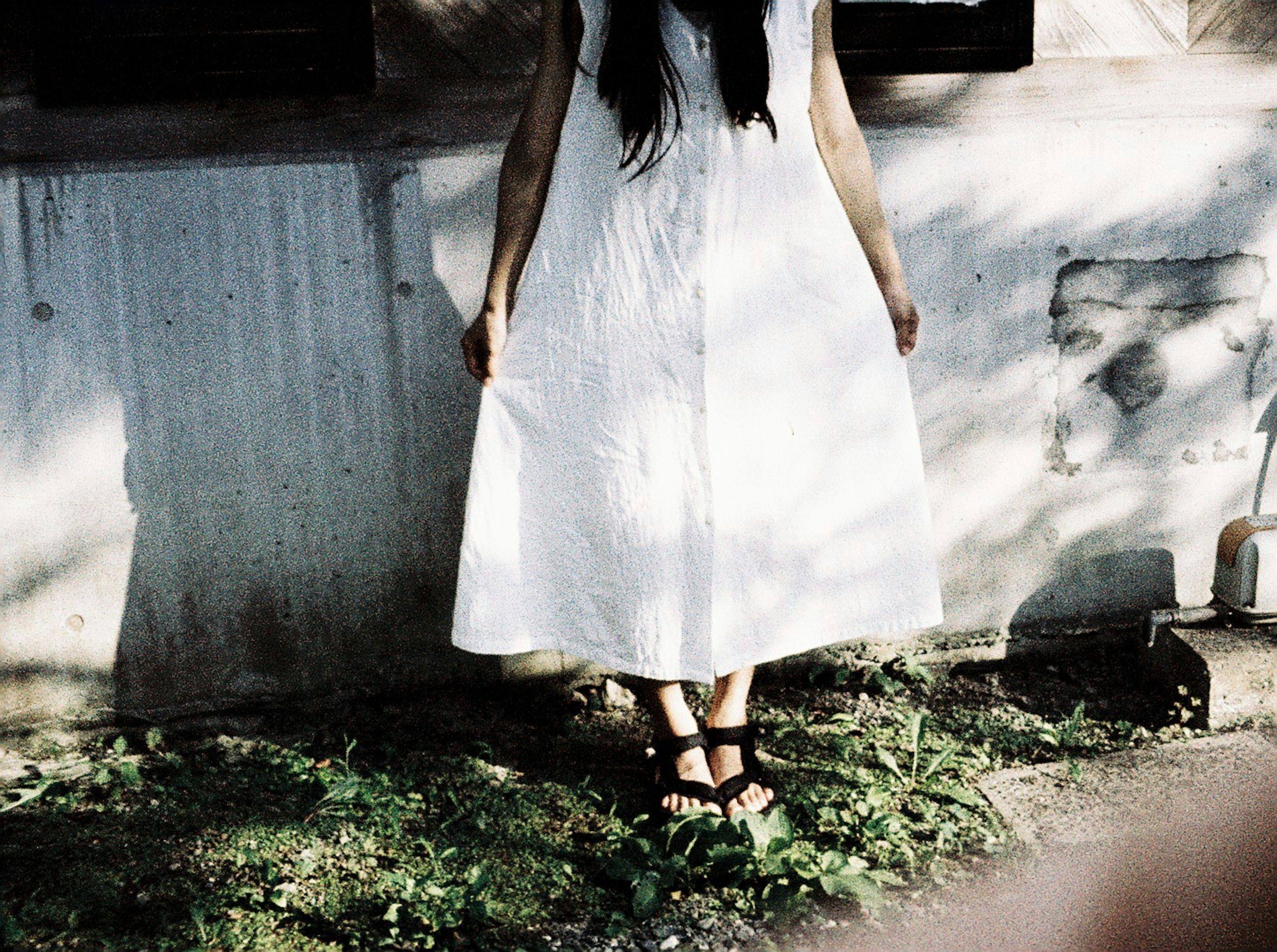 Mujer con vestido blanco de pie sobre la hierba