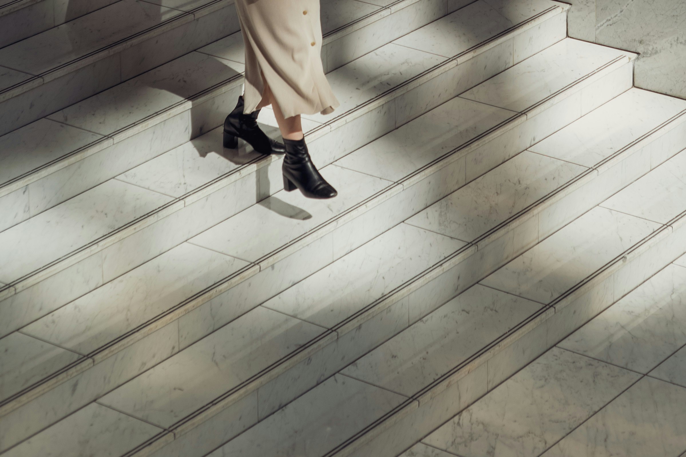 A woman's feet descending stairs with contrasting shadows