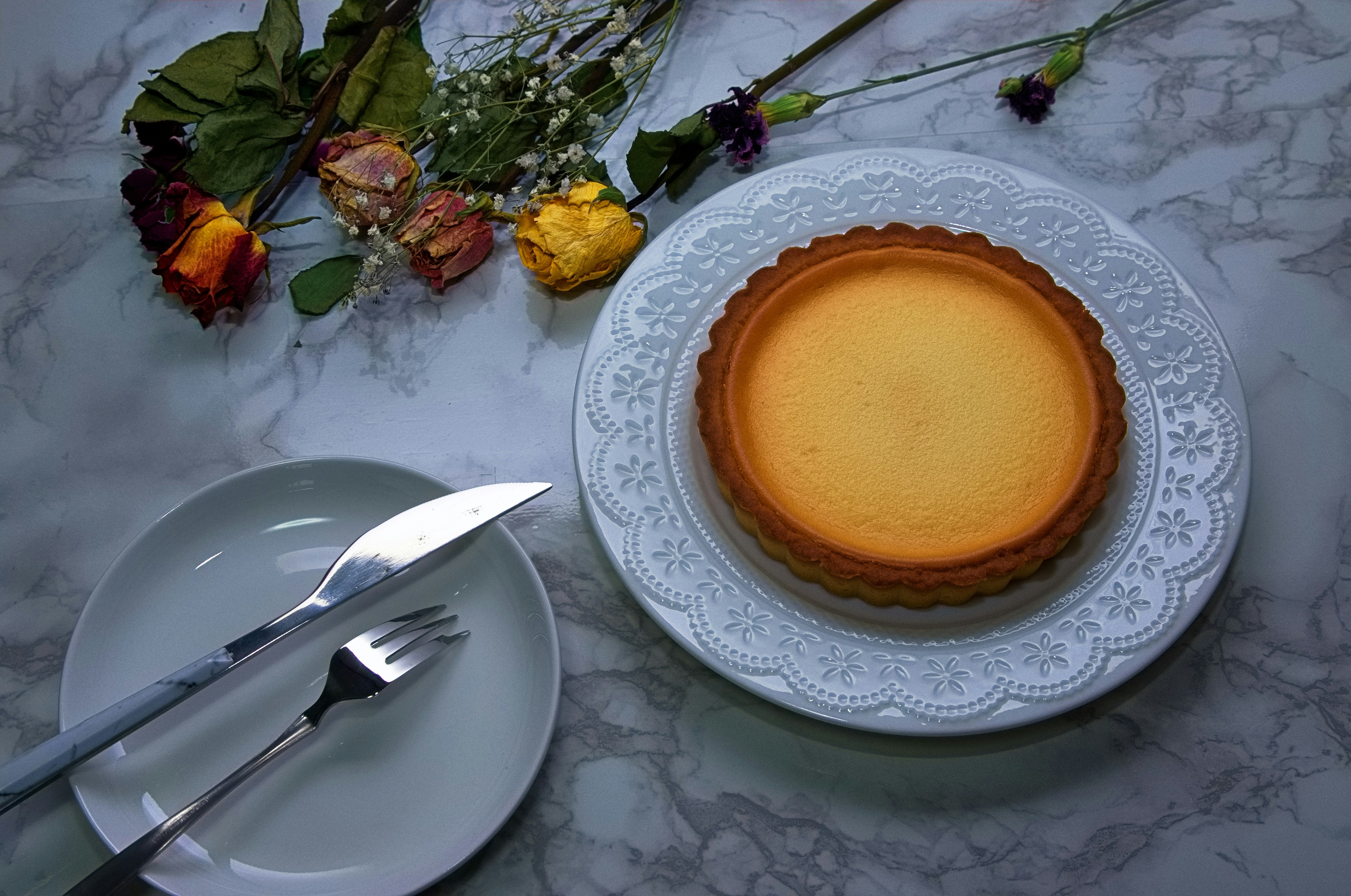 A beautiful tart placed on a white plate with floral decorations