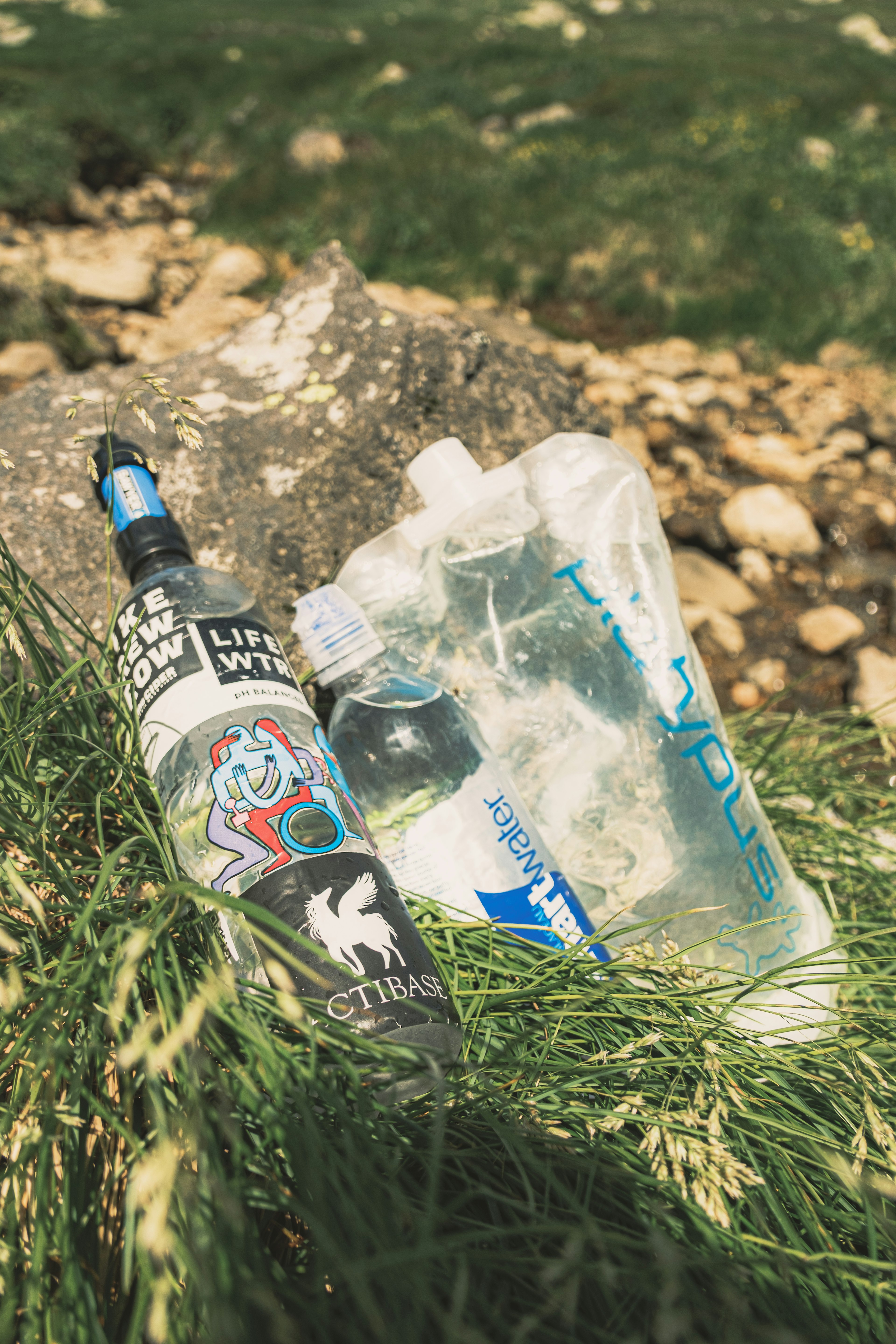 Une bouteille d'eau et un sac d'hydratation reposant sur de l'herbe verte