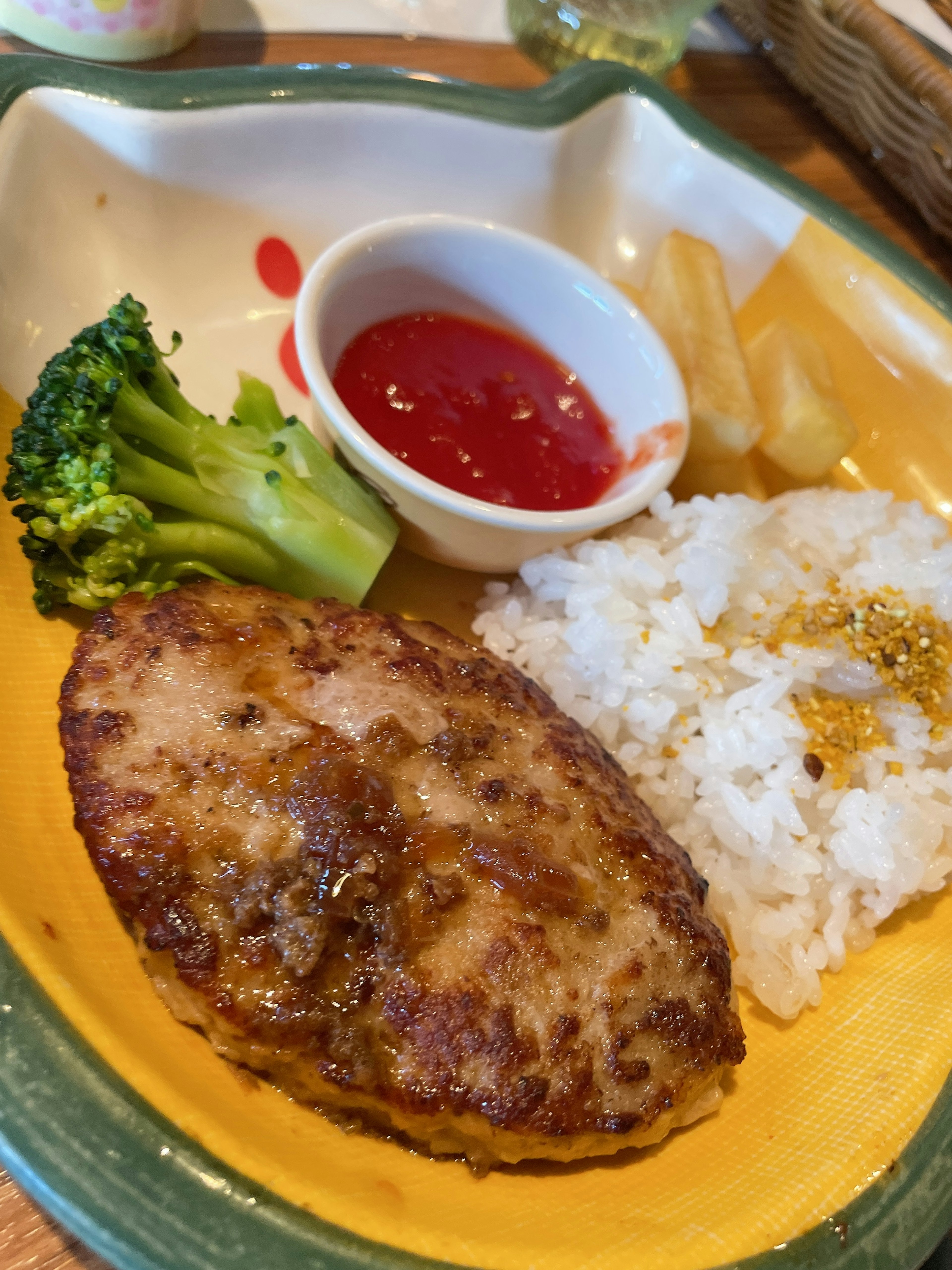 Sebuah steak hamburger yang lezat disajikan dengan nasi putih brokoli saus tomat dan kentang goreng di piring berwarna