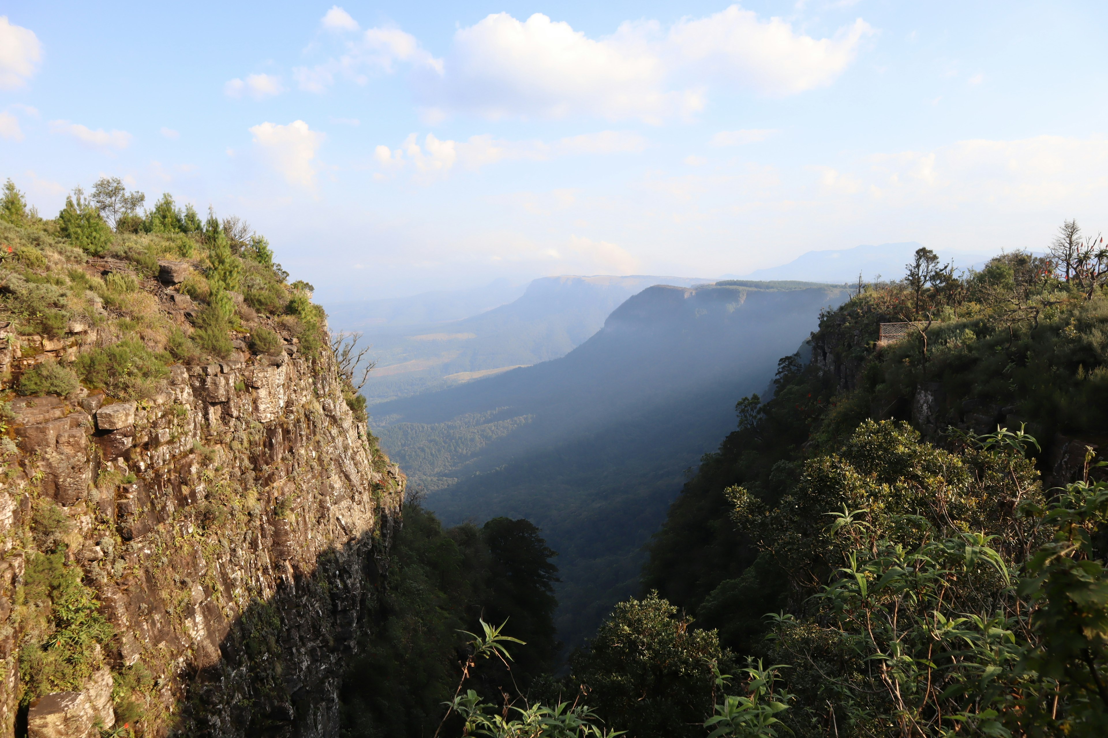 Expansive landscape viewed from a mountain gorge under a blue sky